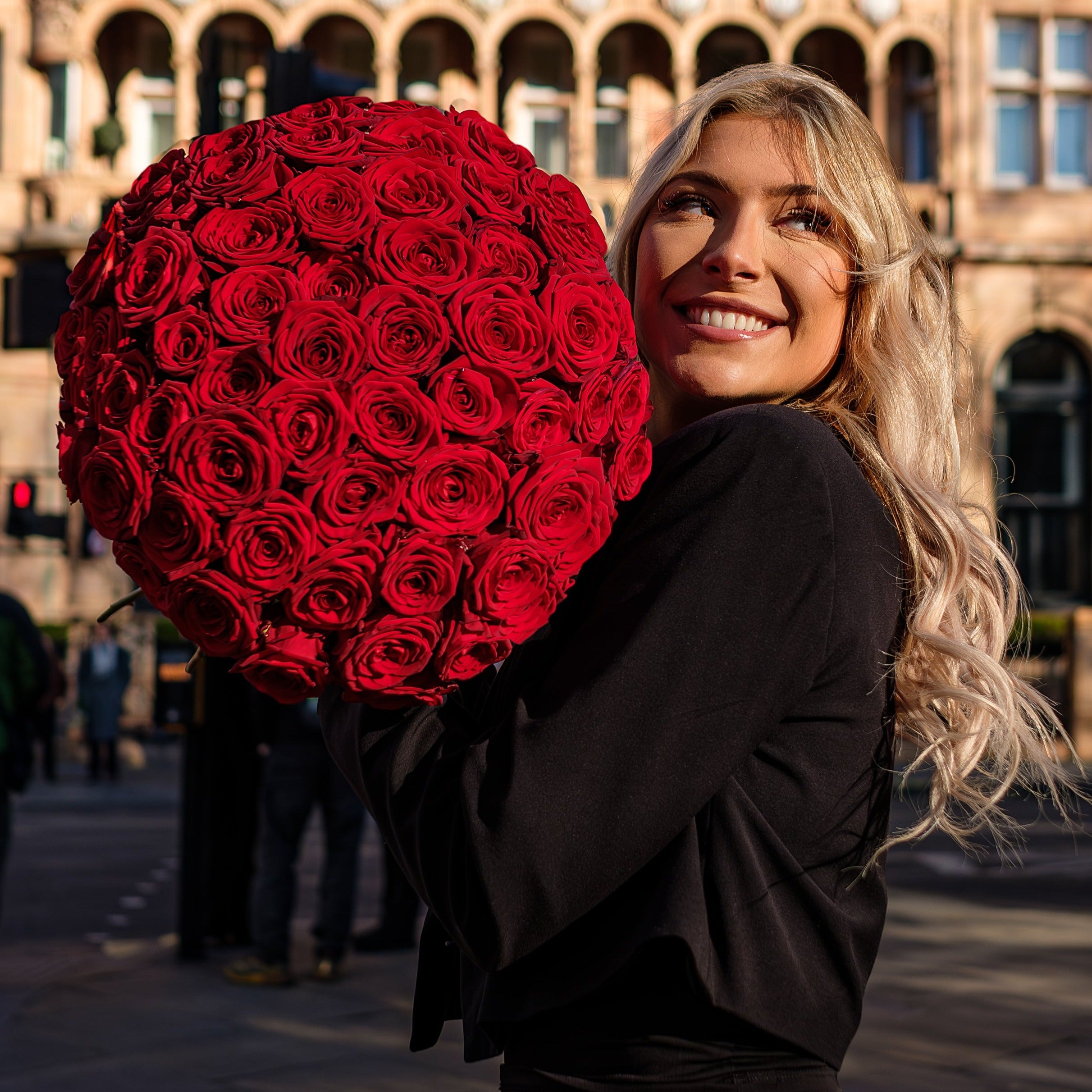 Exceptionally luxurious bouquet of bright red roses; each rose carefully selected for its vibrant colour and impressive size. The sheer number of roses creates a stunning visual impact, with the blooms densely arranged to form a perfect sphere. This meticulous design showcases the roses in full glory, emphasizing their lush, velvety petals which are synonymous with passion and love. Bouquet sizes are from 12 to 200 red roses.