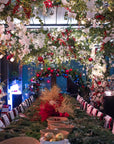 Beautifully decorated wreath-making workshop venue filled with Christmas flowers, festive greenery, and hanging baubles in red, white, and blue.