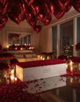 Romantic Valentine's surprise by Amaranté London featuring hundreds of red roses in glass vases, metallic heart balloons, candlelight and rose petal carpet