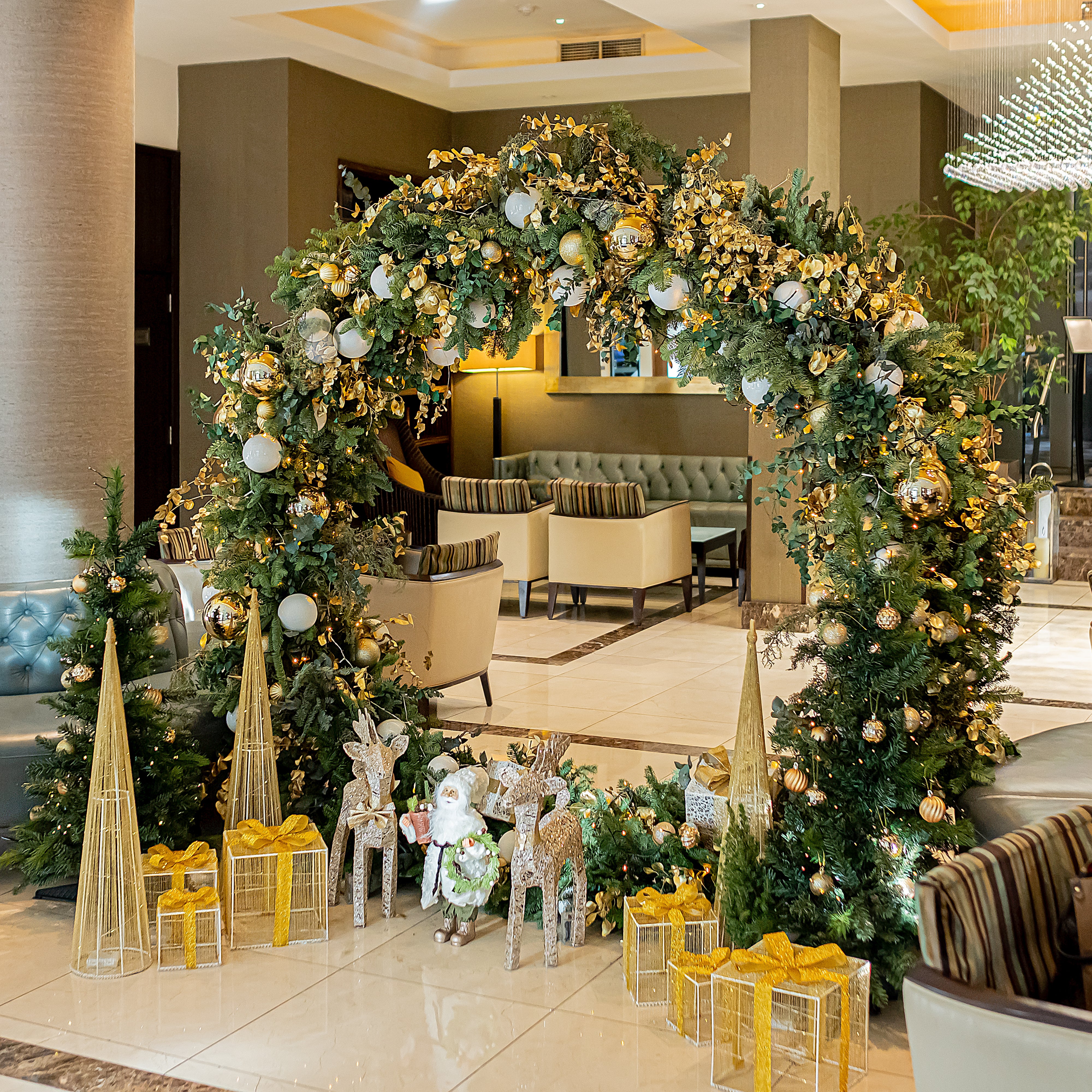 A sustainable bespoke Christmas wreath installation by event florist Amaranté London with green and gold stems.