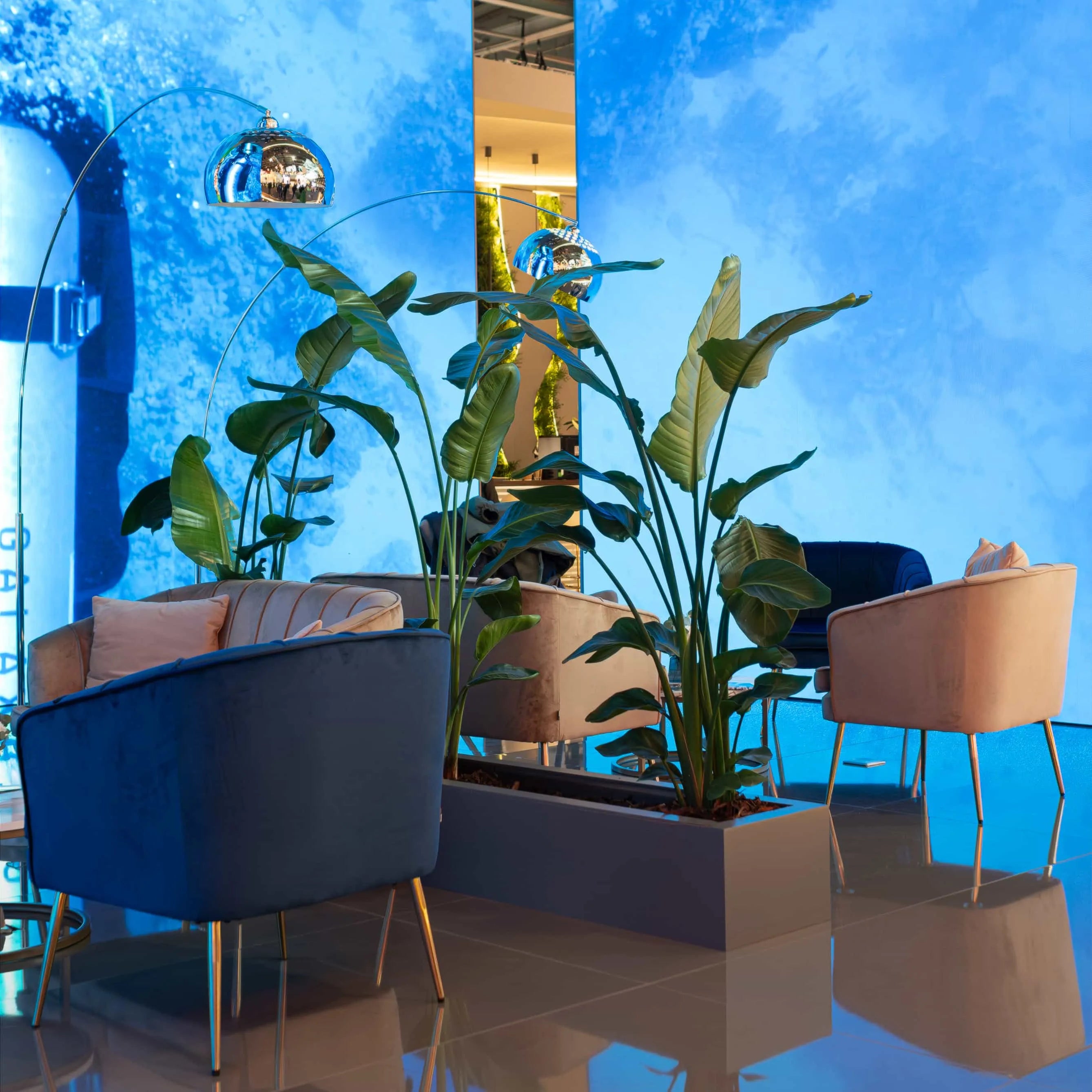 Modern lounge space at The WTM in London is framed by towering Monstera plants juxtaposed with sleek furniture and vibrant lighting - plant hire by event florist Amaranté London.