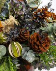 Close-up of a festive wreath with pine cones, green apples, and other decorative elements.