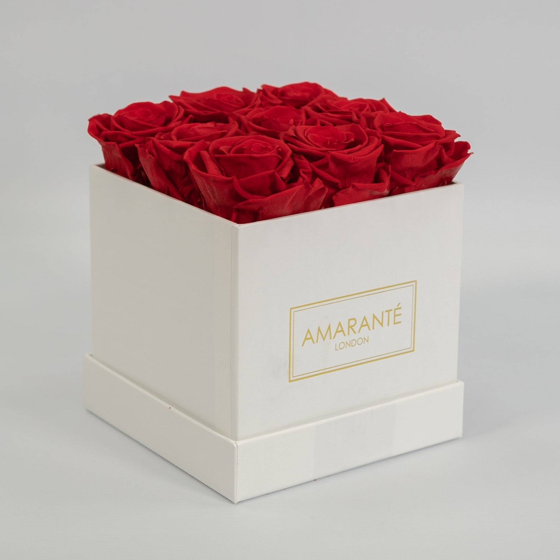 Divine red roses entrenched in a dapper white medium hatbox in square 