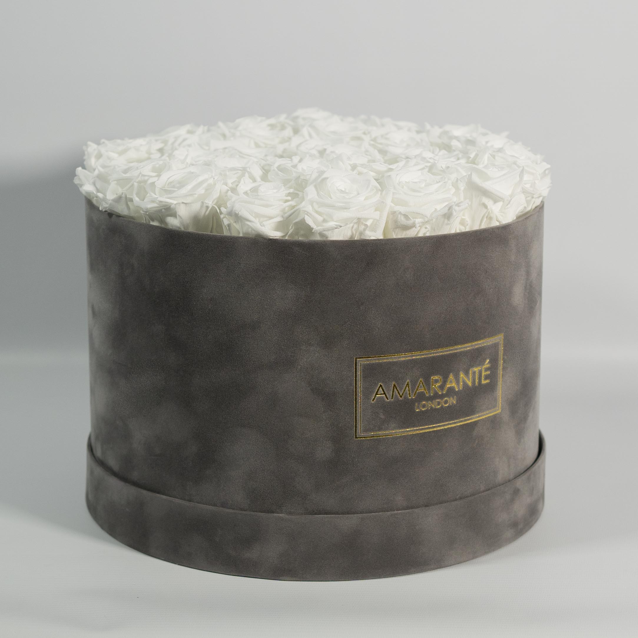 Dapper white Roses in a stylish grey box, denoting clarity, simplicity, and class.