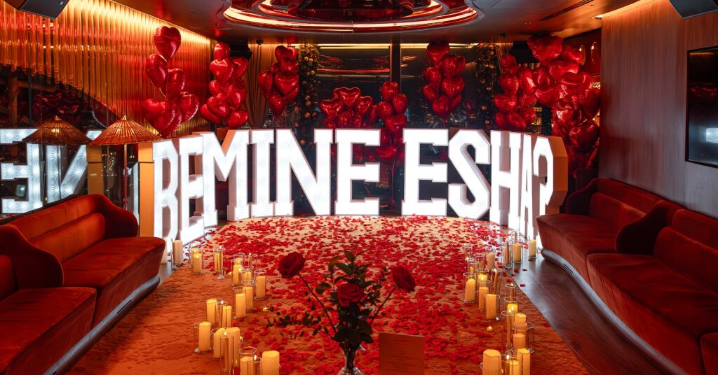 Behind the scenes of a romantic marriage proposal at Sushi Samba London featuring cascading rose petals, illuminated Be Mine display, heart-shaped balloons, and candlelight - Amaranté London Events