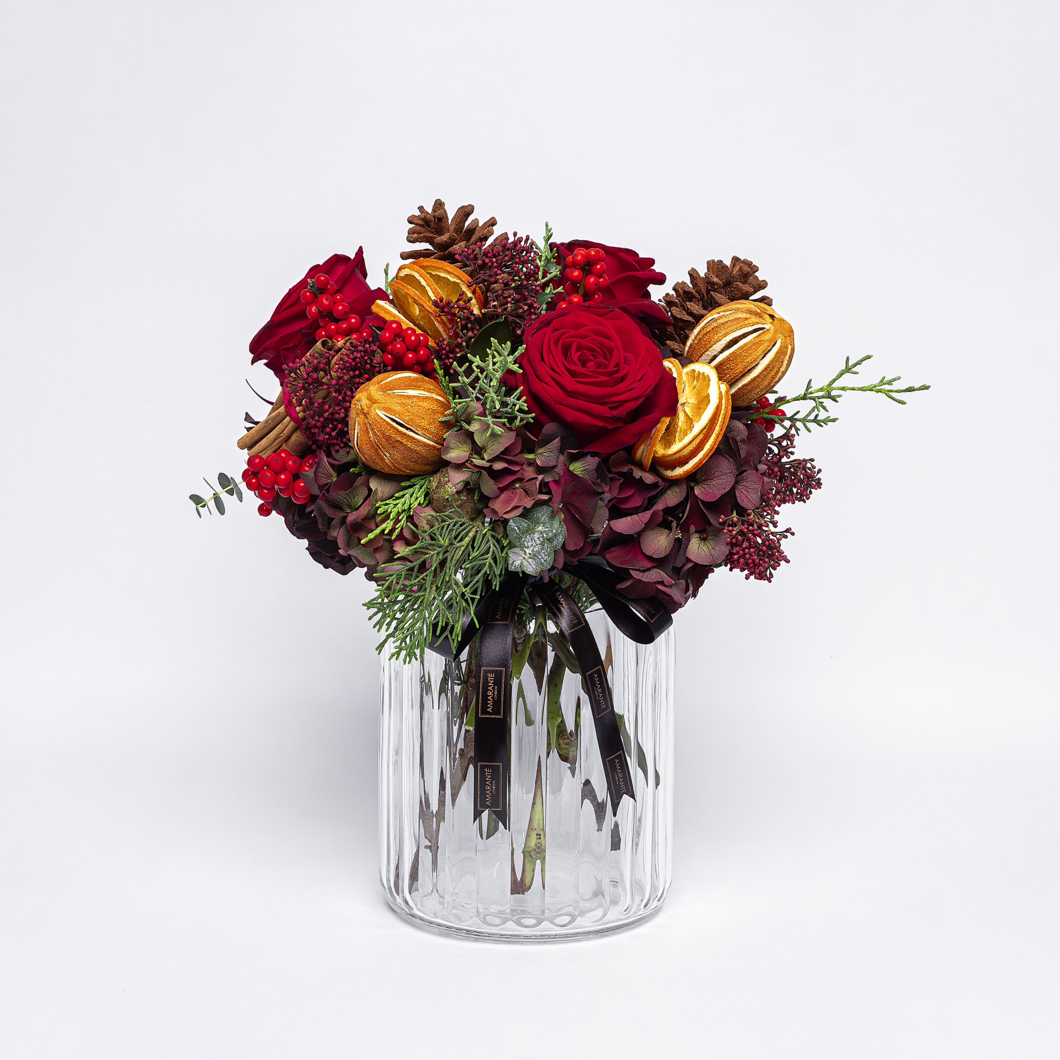 Bouquet of red and gold flowers in a clear glass vase on a white background