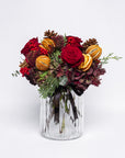 Bouquet of red and gold flowers in a clear glass vase on a white background