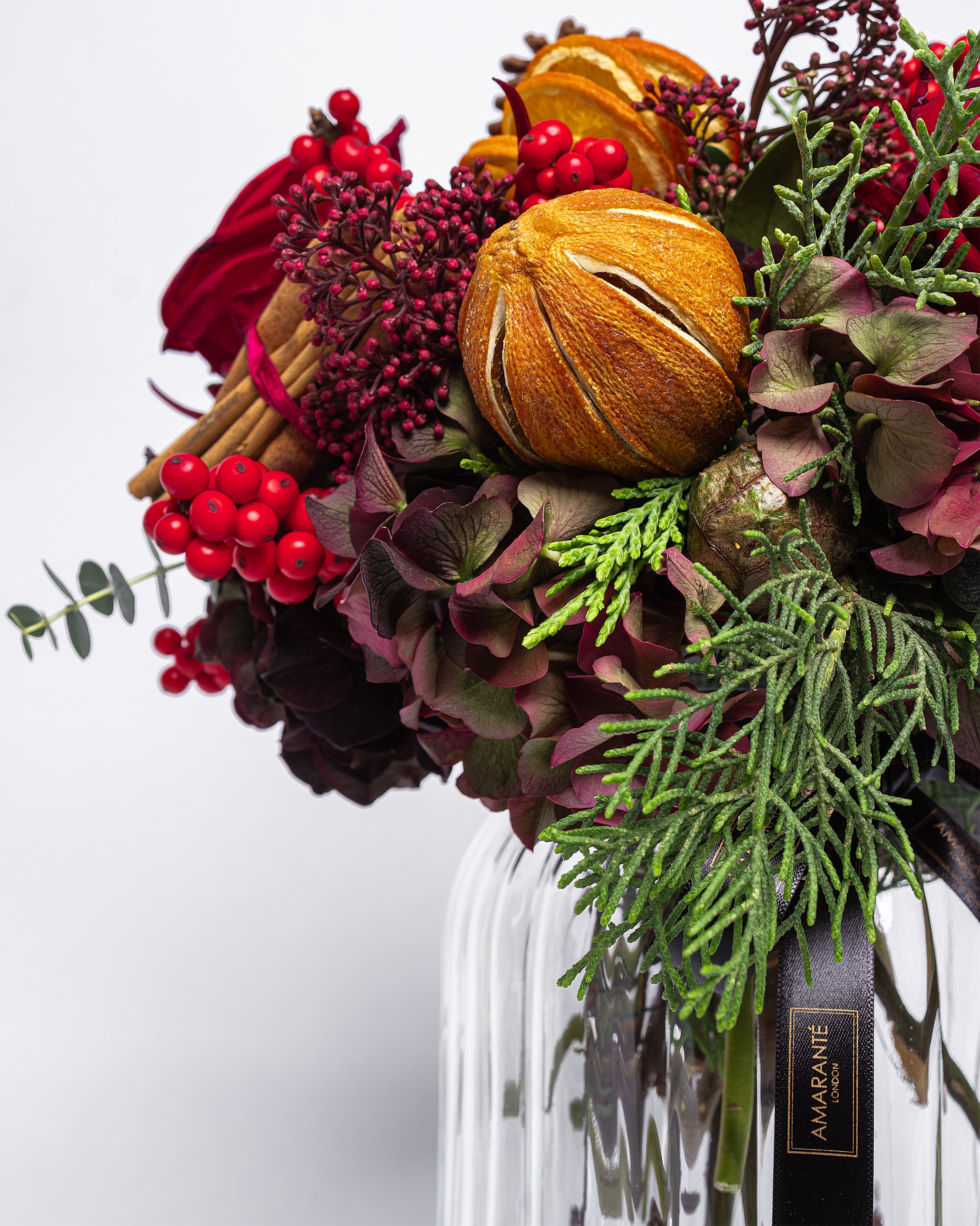 Bouquet of flowers with fruits and berries in a clear vase on a white background