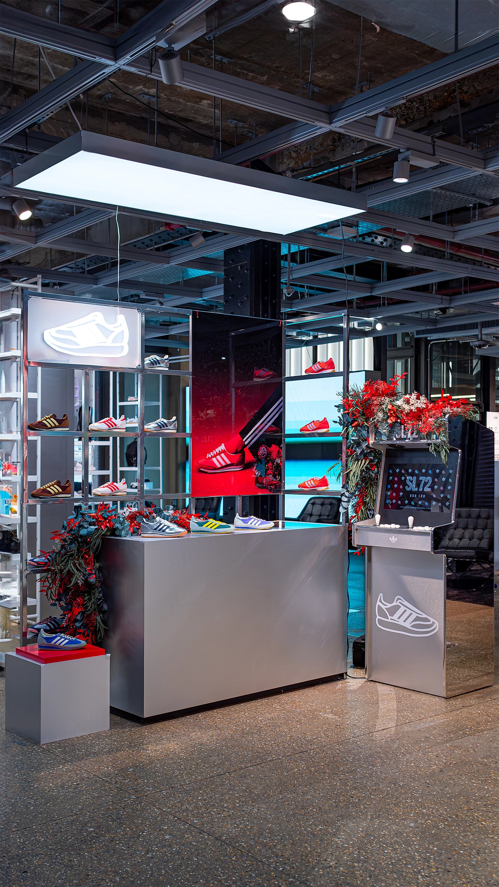 A broad view of the Adidas Bond Street store SL72 collection event, highlighting the many floral installations by Event Florist Amaranté London. The bespoke store decoration décor includes red and blue floral accents, creating a vibrant backdrop for Adidas products.