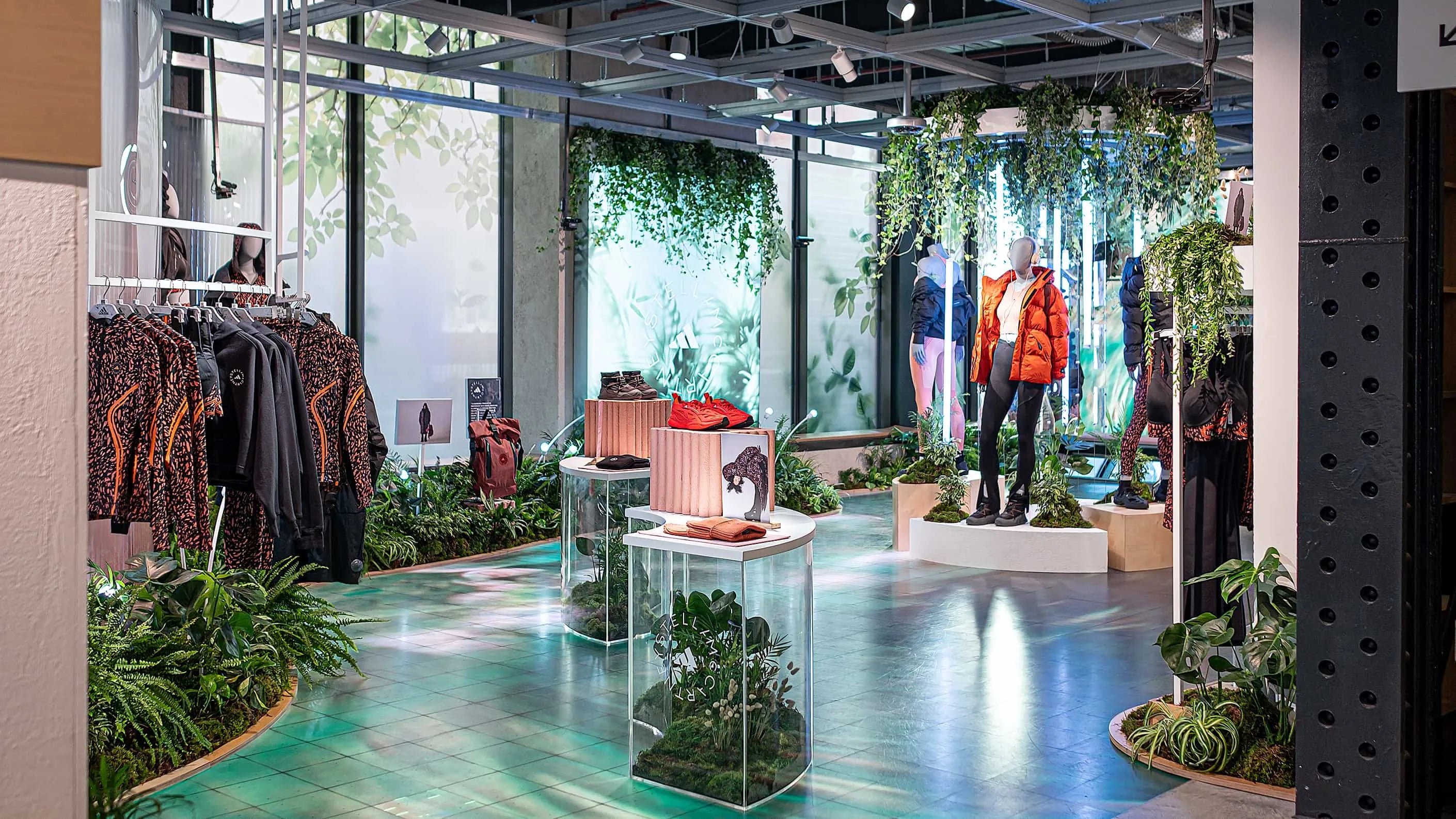 Amaranté London displays its sophisticated event floristry at Adidas x Stella McCartney's aSMC collection launch, with vibrant plant displays intertwining with the fashion-forward athletic wear. The ambience reflects a luxury storefront with a biophilic design approach.