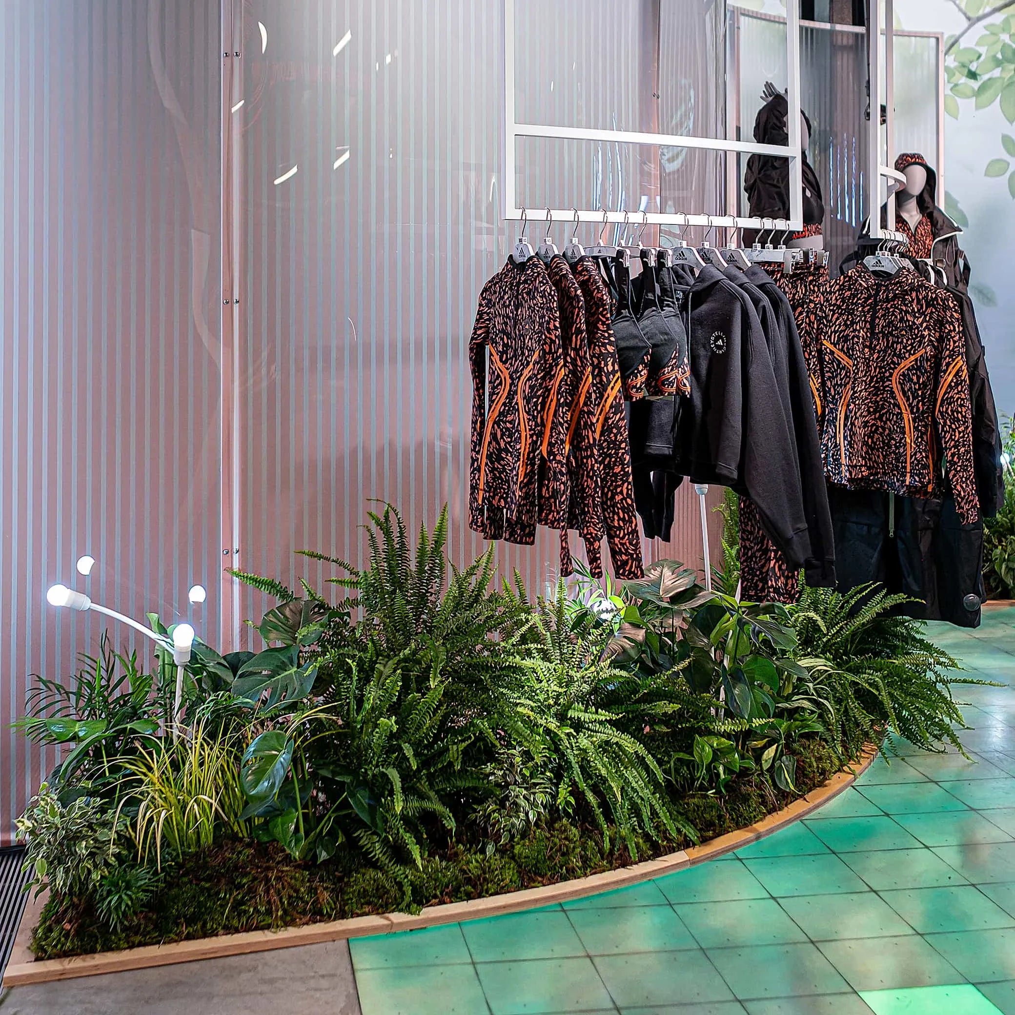 A view of the retail space featuring a verdant display of ferns and foliage subtly merging high fashion with the natural world - designed and installed by Amaranté London at the Adidas x Stella McCartney aSMC collection launch.