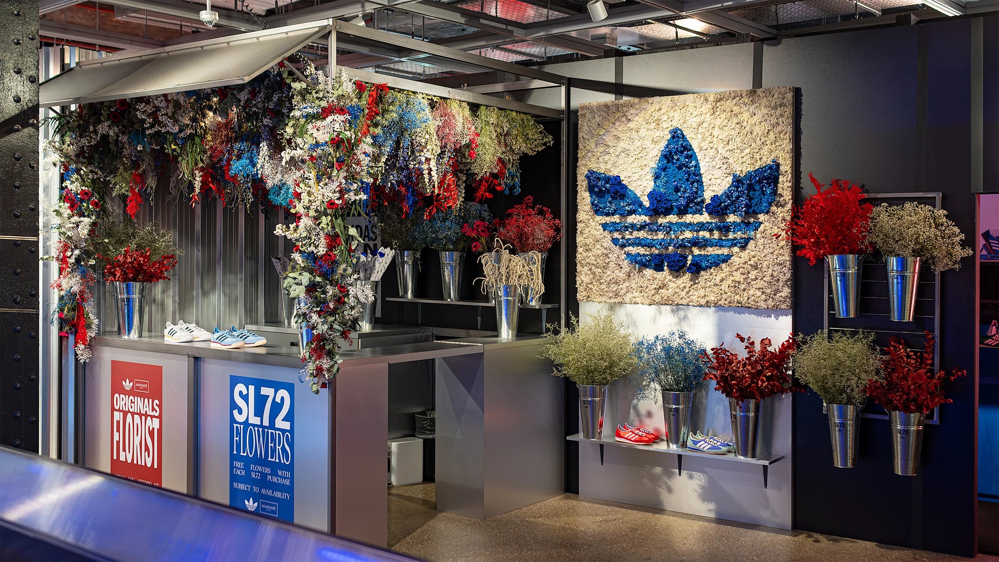 A custom floral arrangement by Event Florist Amaranté London was displayed at the Adidas Oxford Street Store. The arrangement features flowers in red, white, and blue. Adidas SL72 branding is visible, showcasing the integration of florals with the brand identity.