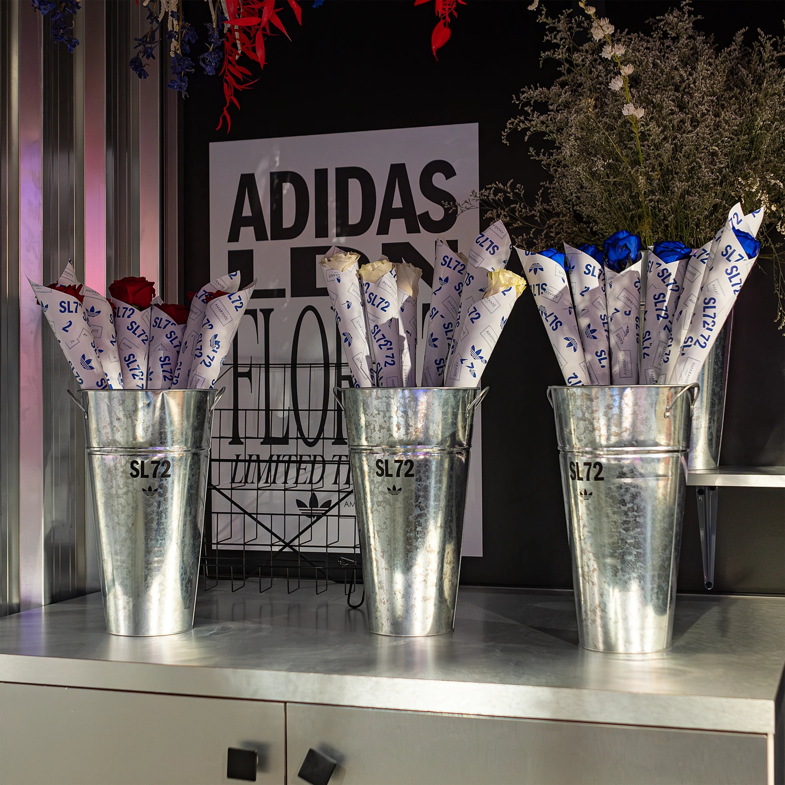 Metal planters with red, blue and yellow infinity roses, complement the modern retail space's aesthetic - Amaranté London