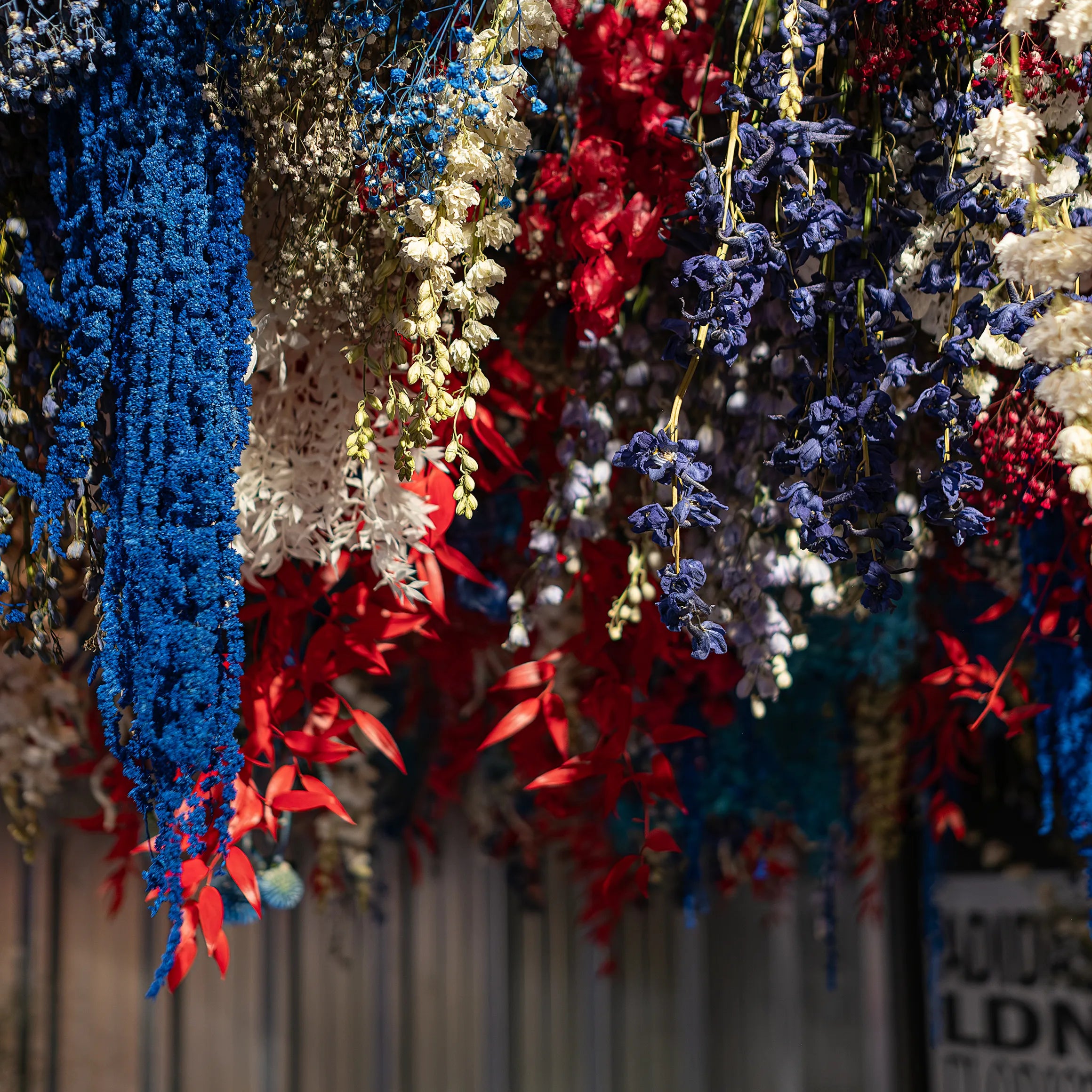Close-up of vibrant red, white, and blue preserved floral garland created by Event Florist Amaranté London for the Adidas Oxford Street Store SL72 collection launch. This custom floral arrangement was designed to add an artistic touch to the store.