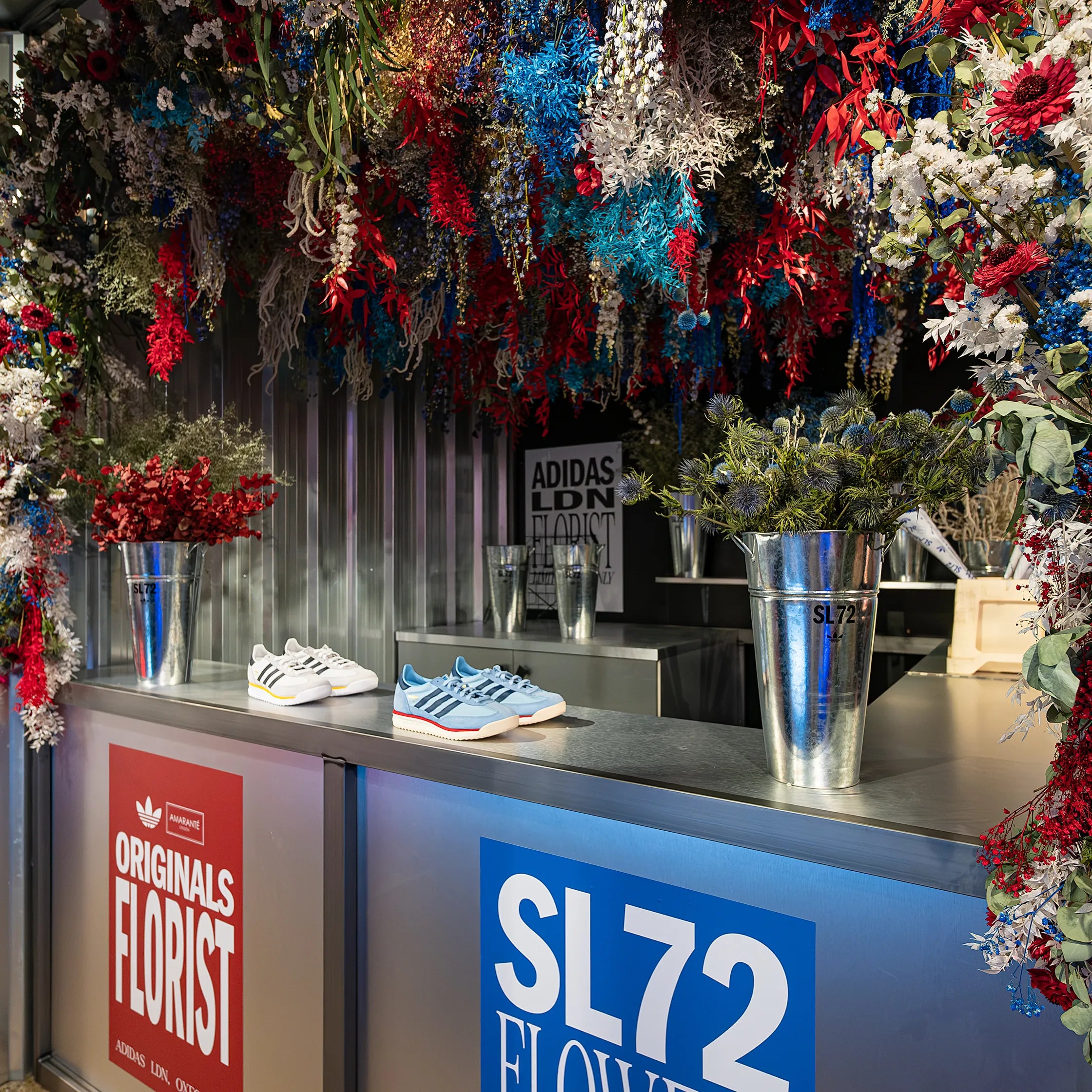 Amaranté London custom floral arrangement for The Adidas SL72 collection launch, showcasing a colourful mix of preserved red, white, and blue flowers in a retail environment. The vibrant colours resonate with the brand, enhancing the shop space to create a dynamic atmosphere.