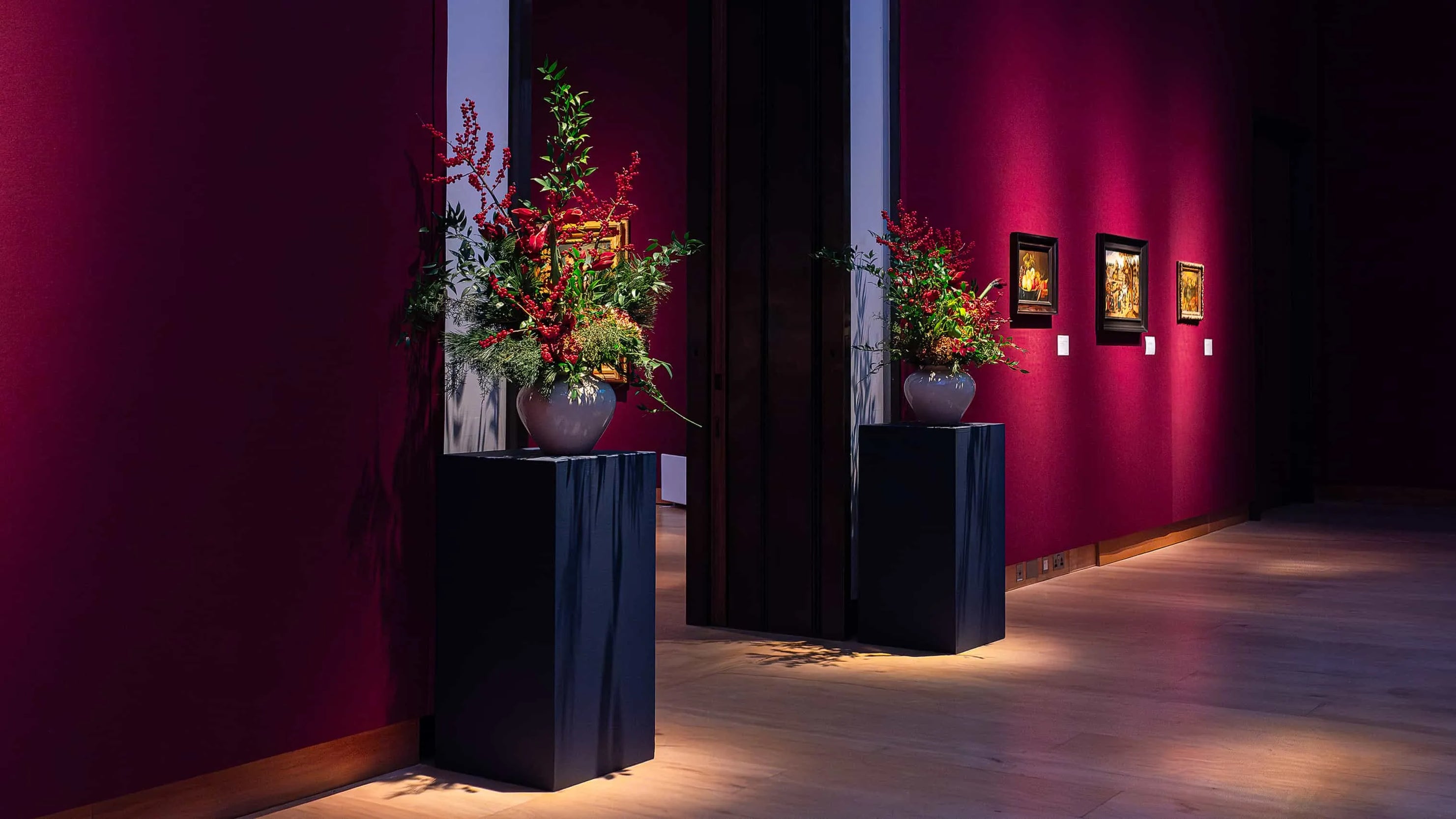 Custom Christmas floral arrangements in purple vases featured under spotlights in the hallroom at Christie's