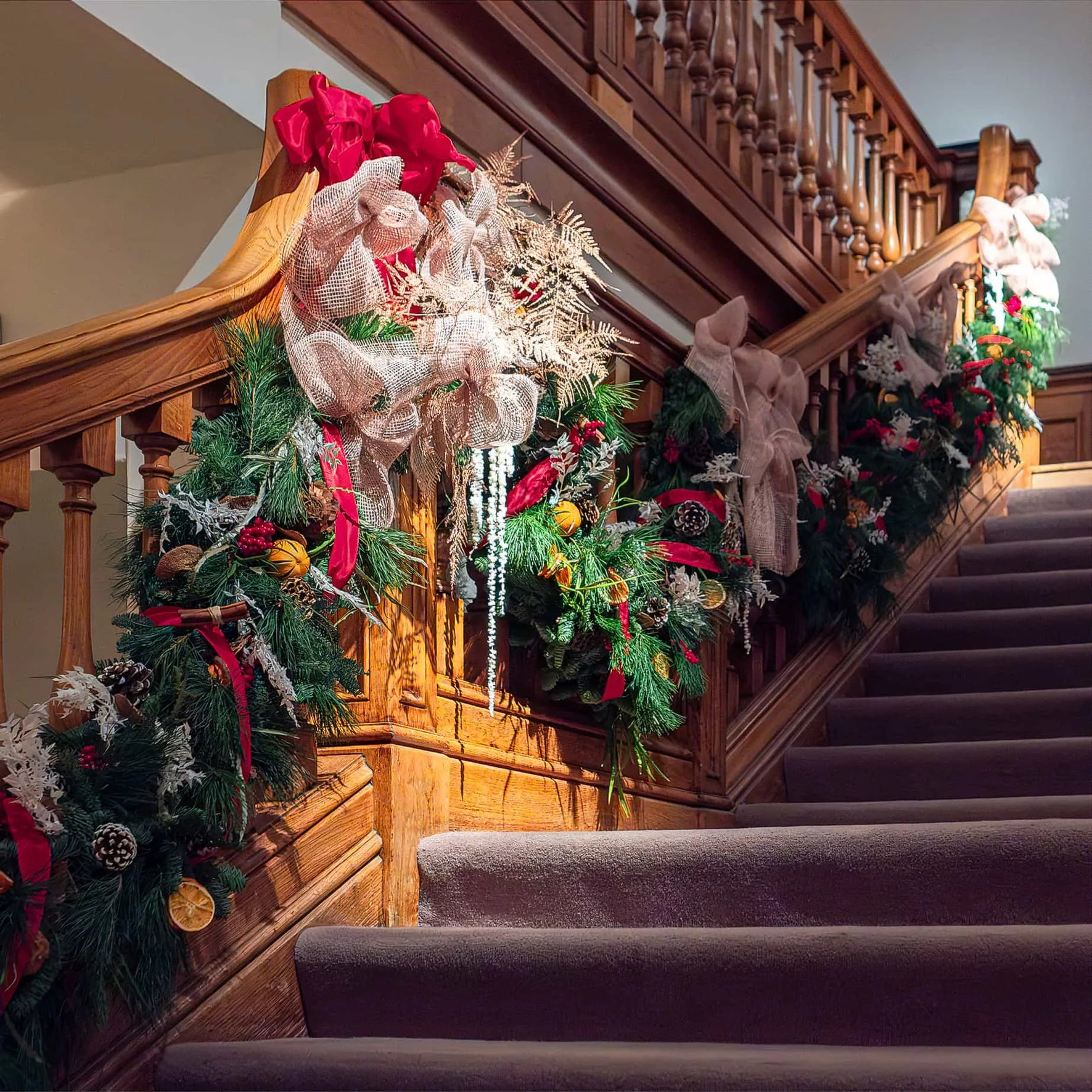 Closeup view of our Christmas Flowers decorating this wide wooden staircase at Christie's