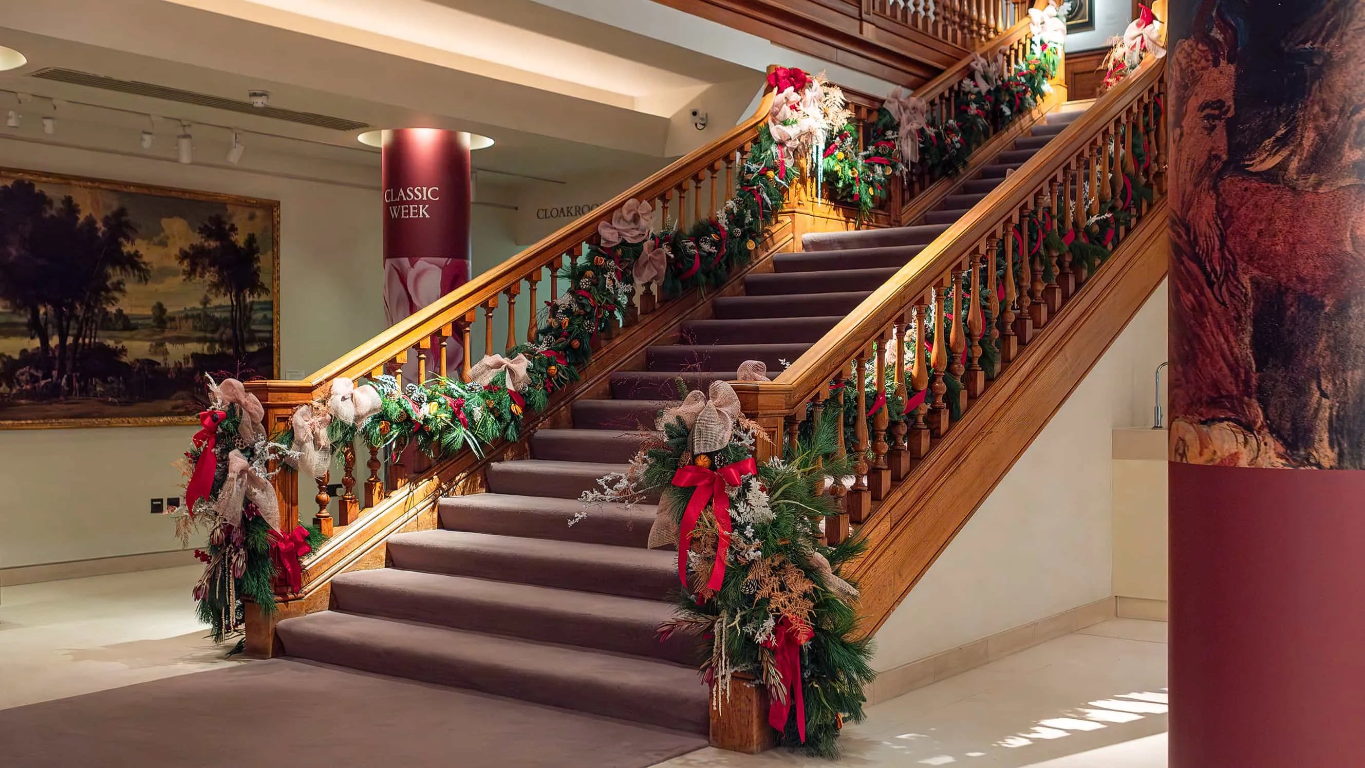 Cascading Christmas Flowers, a combination of seasonal reds and lush greenery gracefully adorn this wide wooden staircase, creating an elegant and timeless floral spectacle.