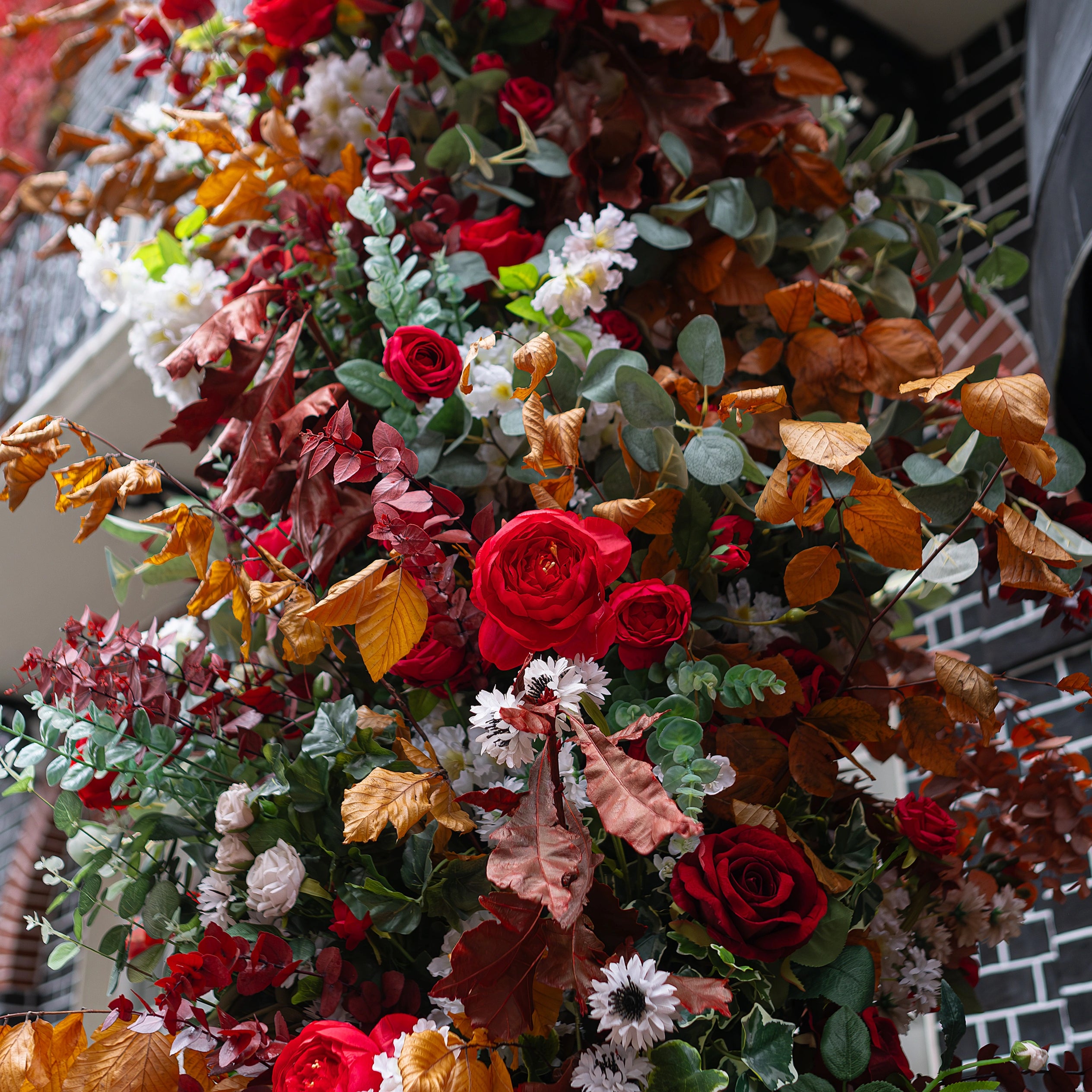 A detailed view of the flowers for the floral archway for Crown London. In the image, the deep red roses blend with the eucalyptus, autumn foliage, and pumpkins for a warm seasonal greeting to club members at the Curzon Street entrance.