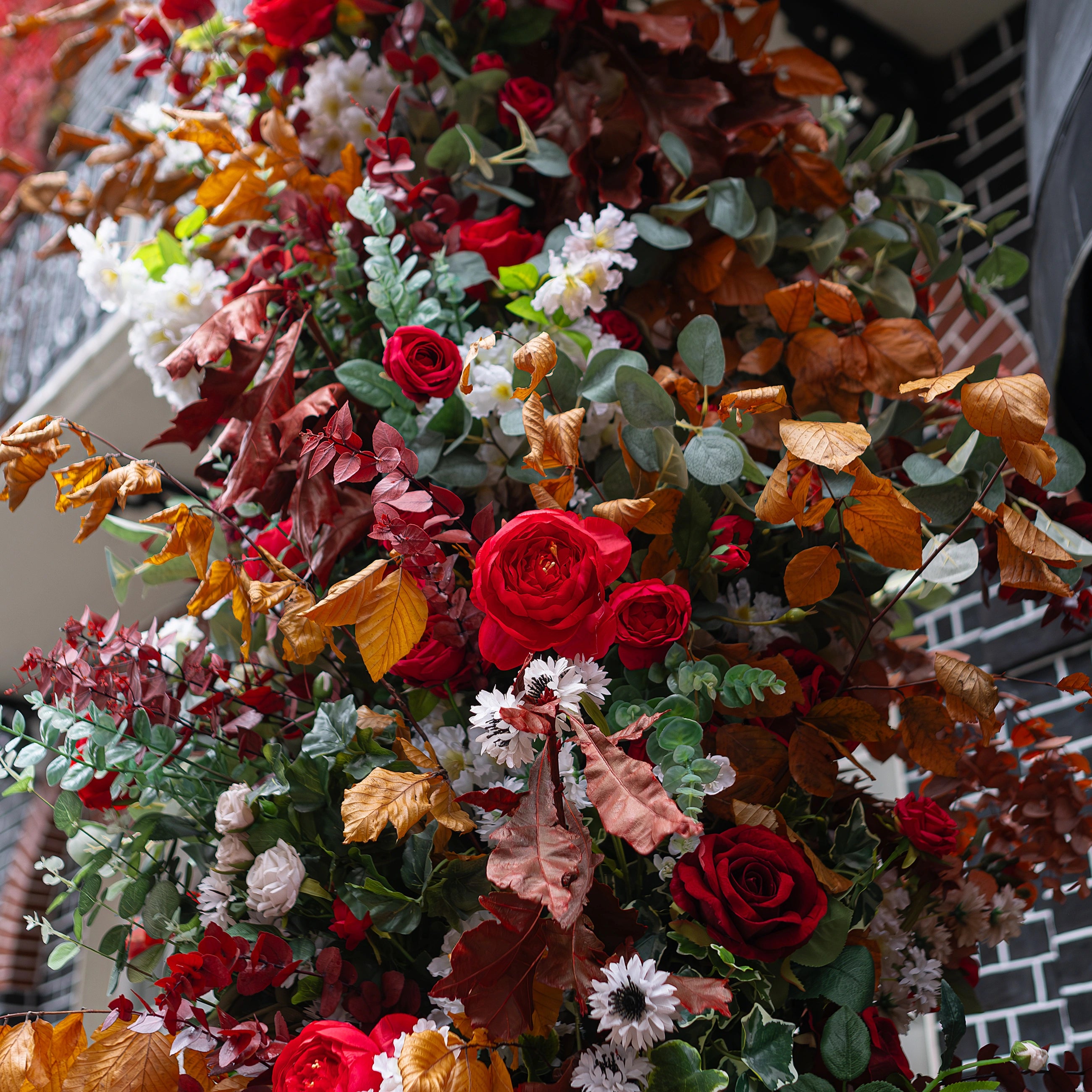 A detailed view of the flowers for the floral archway for Crown London. In the image, the deep red roses blend with the eucalyptus, autumn foliage, and pumpkins for a warm seasonal greeting to club members at the Curzon Street entrance.