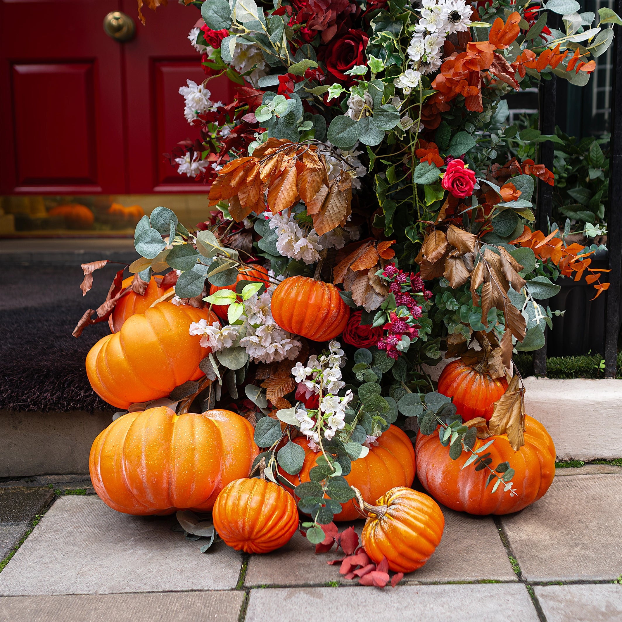 Close-up view of the seasonal décor featuring bright orange pumpkins - Floral arch design, creation and installation by Event Florist Amaranté London.
