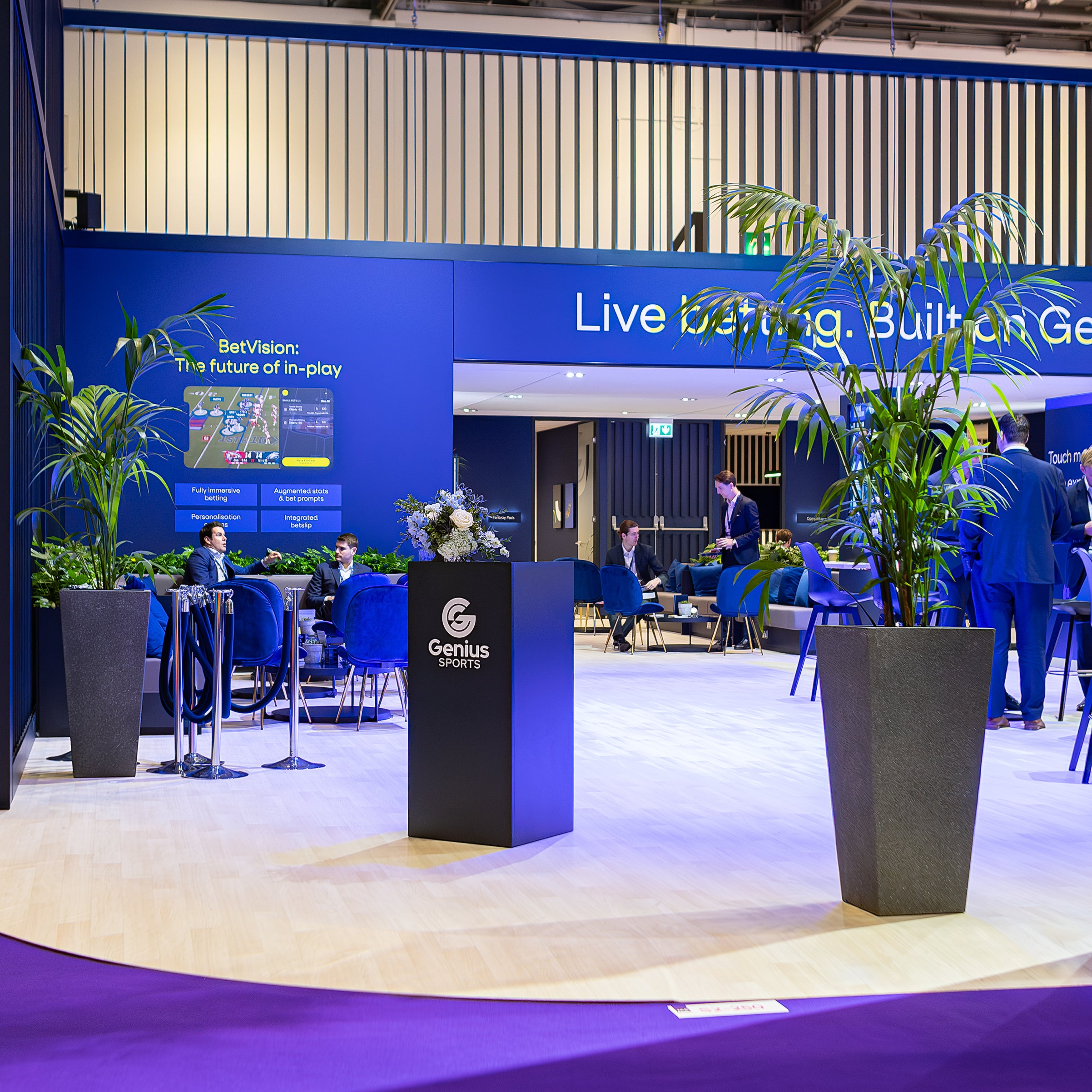The Genius Sports booth at ICE London Exhibition features an inviting lounge area decorated with our lush tropical plants and an elegant bespoke floral arrangement, embodying the fusion of luxury and technology in the gaming industry.