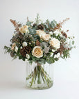 Bouquet of flowers with roses and greenery in a clear vase on a white background