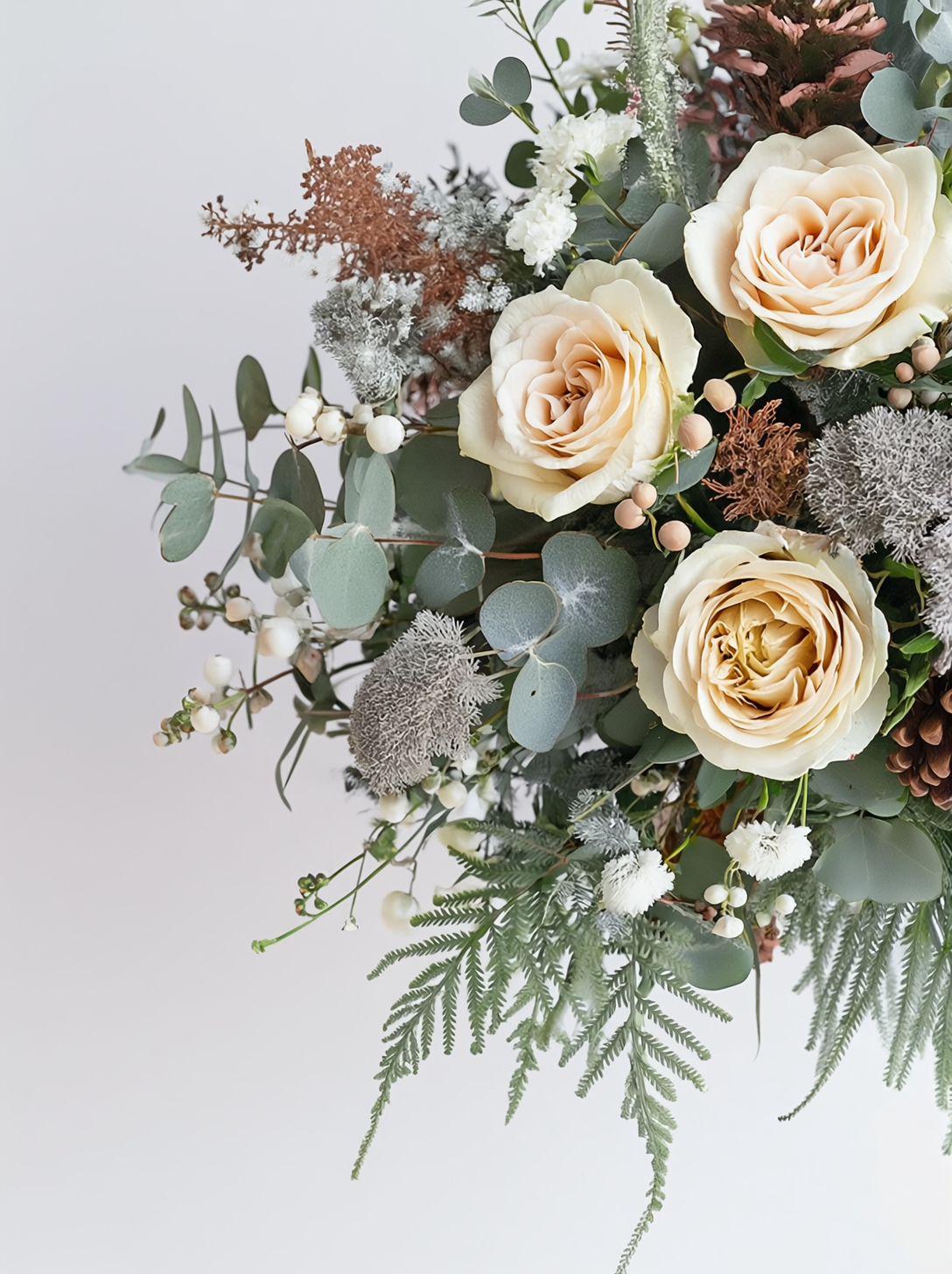 Bouquet of flowers with roses, eucalyptus, and other greenery on a light background