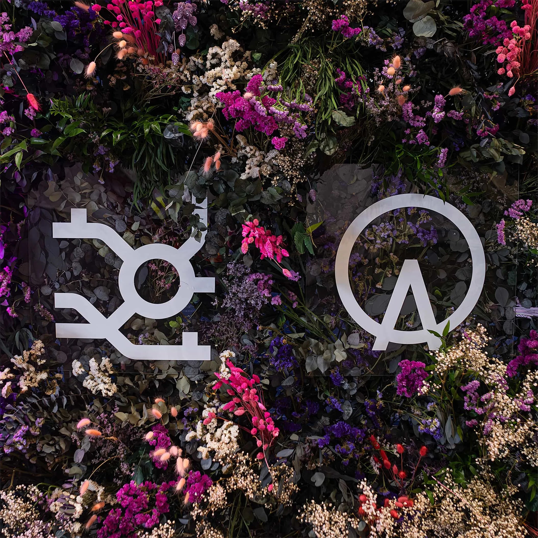 An artistic floral display at the Formula E event featured logos intertwined with a variety of flowers and foliage, showcasing creative design and branding integration - Amaranté London Event Florist.