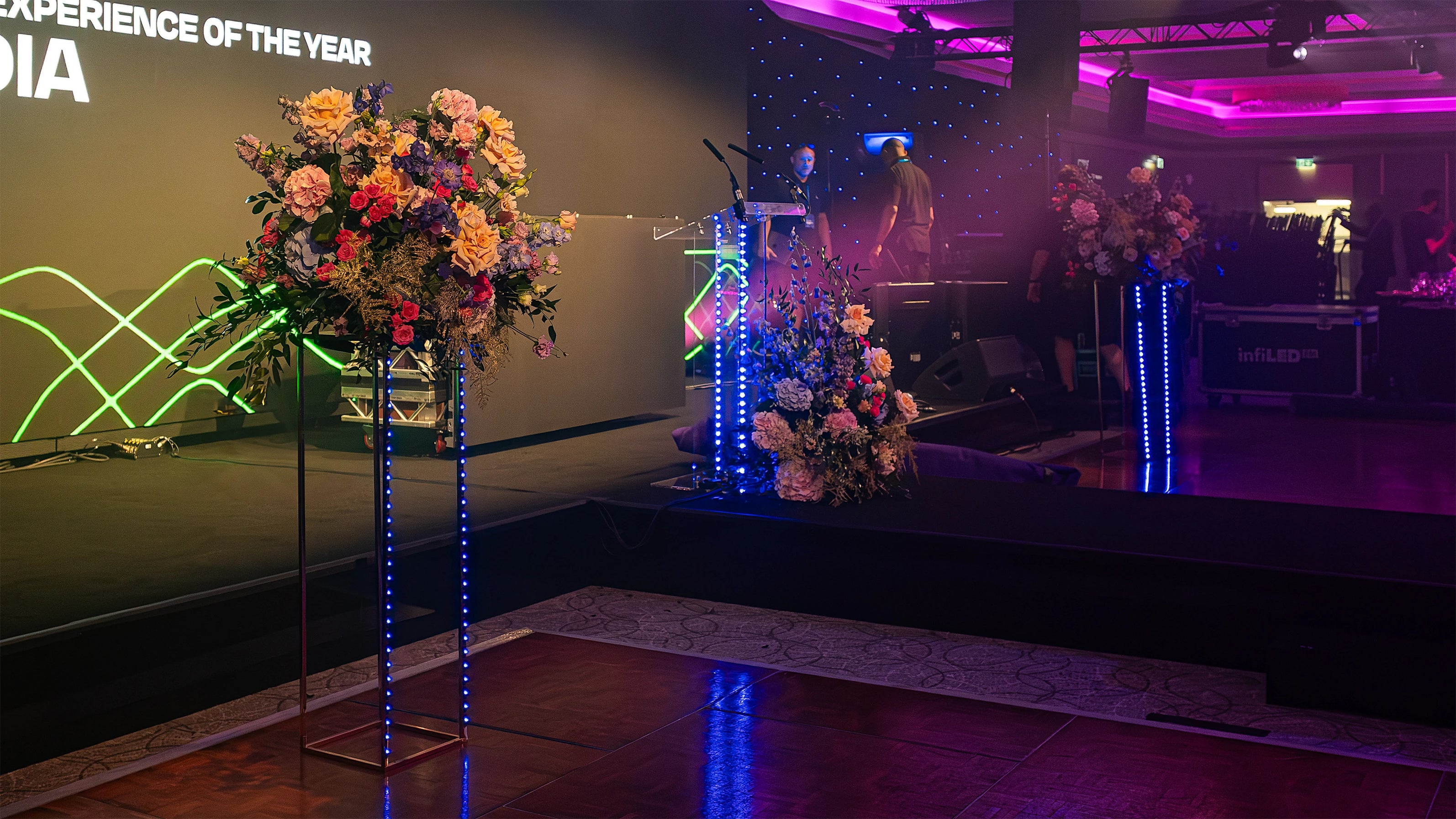 Luxurious floral displays flank a stage with modern lighting, enhancing the ambience for the Formula E Awards presentation; Amaranté London florals add a vibrant, celebratory touch to the Gala Dinner Event in London.