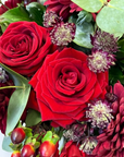Close-up detail of premium red roses and burgundy astrantia flowers with eucalyptus leaves, showcasing the exquisite craftsmanship of luxury floral arrangement - Amaranté London