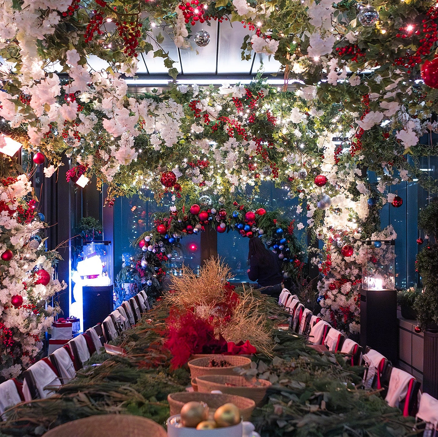 Beautifully decorated wreath-making workshop venue filled with Christmas flowers, festive greenery, and hanging baubles in red, white, and blue.