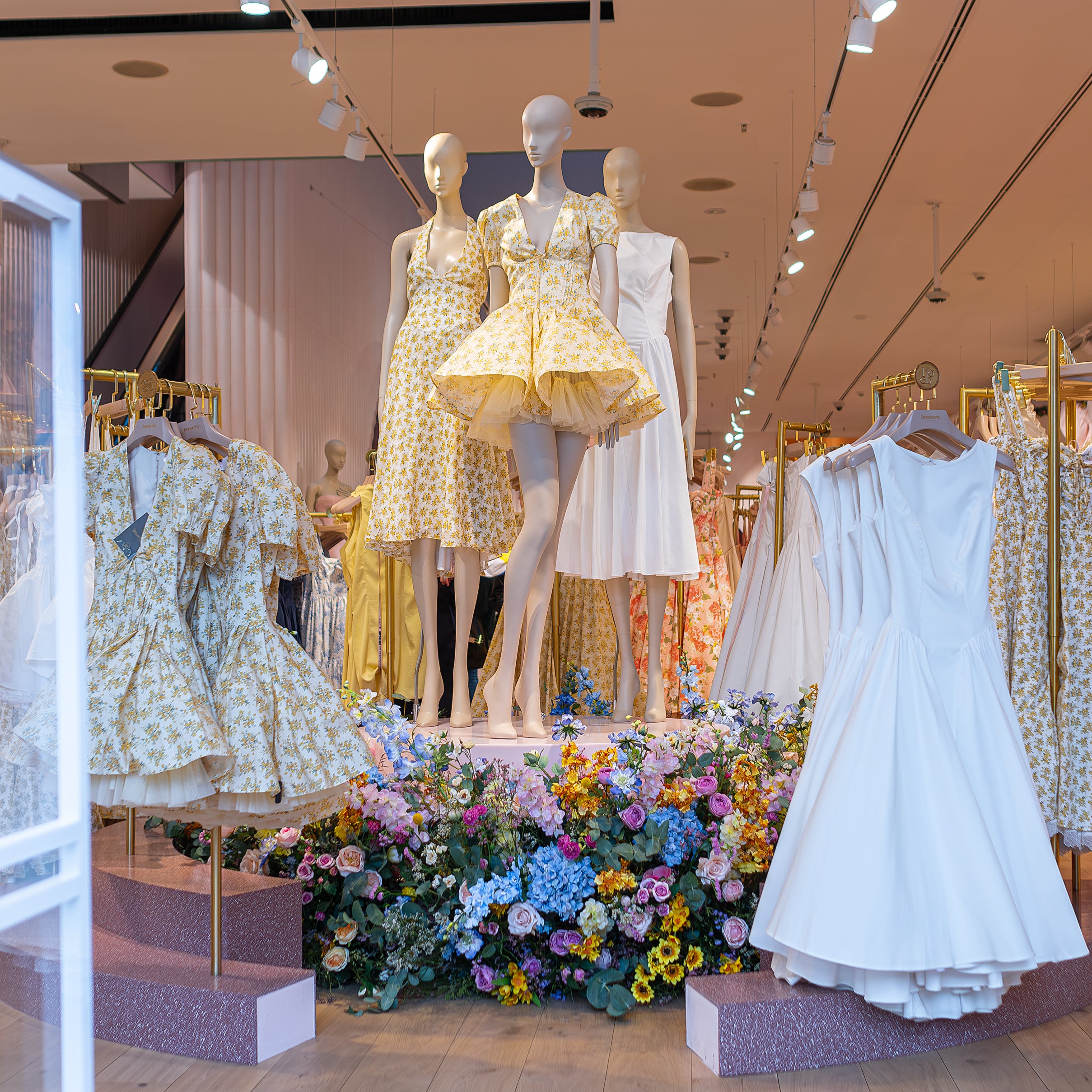 Retail floral installation with mixed seasonal blooms surrounding a mannequin display at House of CB Oxford Street, London by Amarante London
