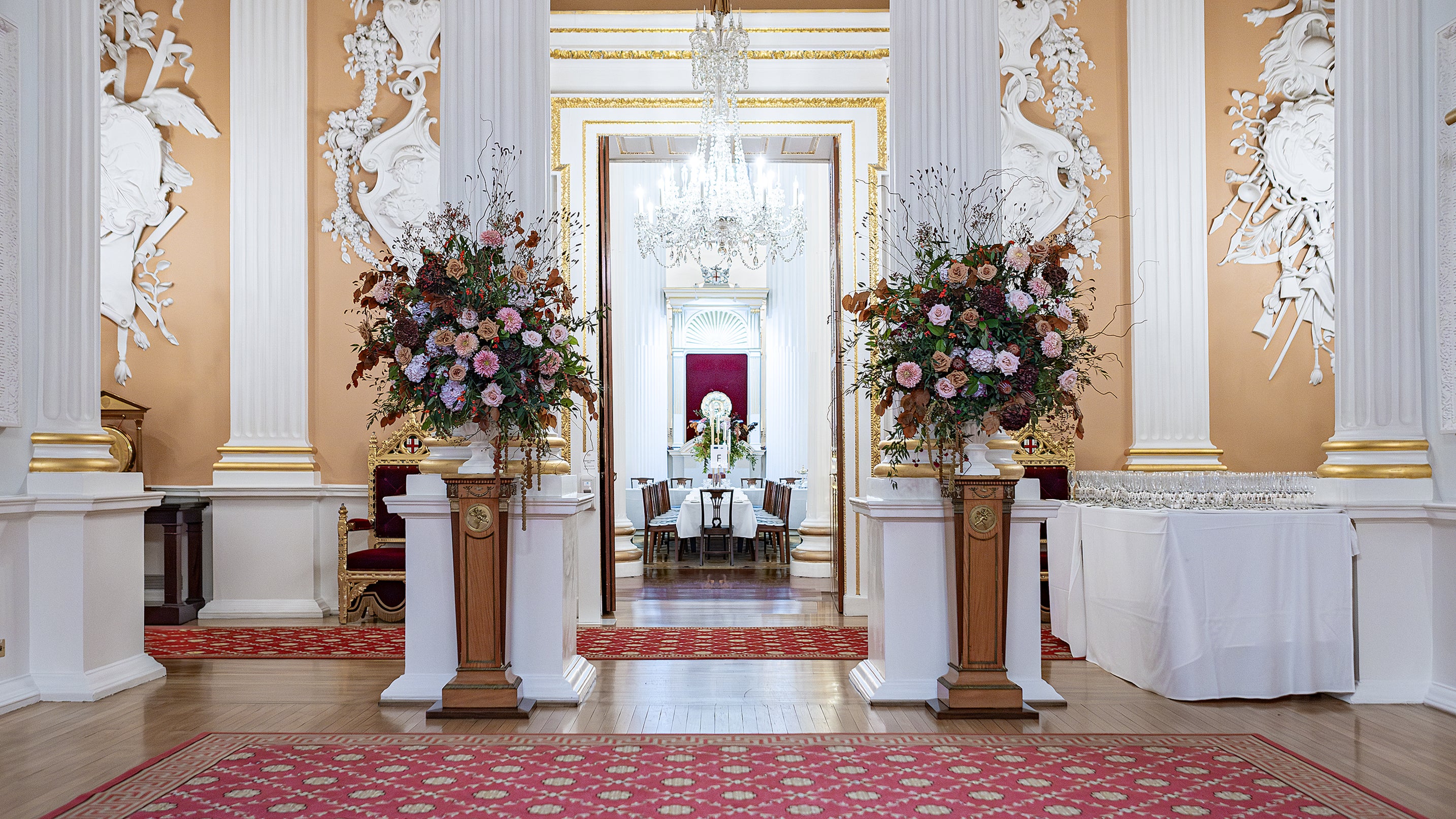 Exquisite bespoke floral arrangements on plinths to welcome guests at the entrance of the event.