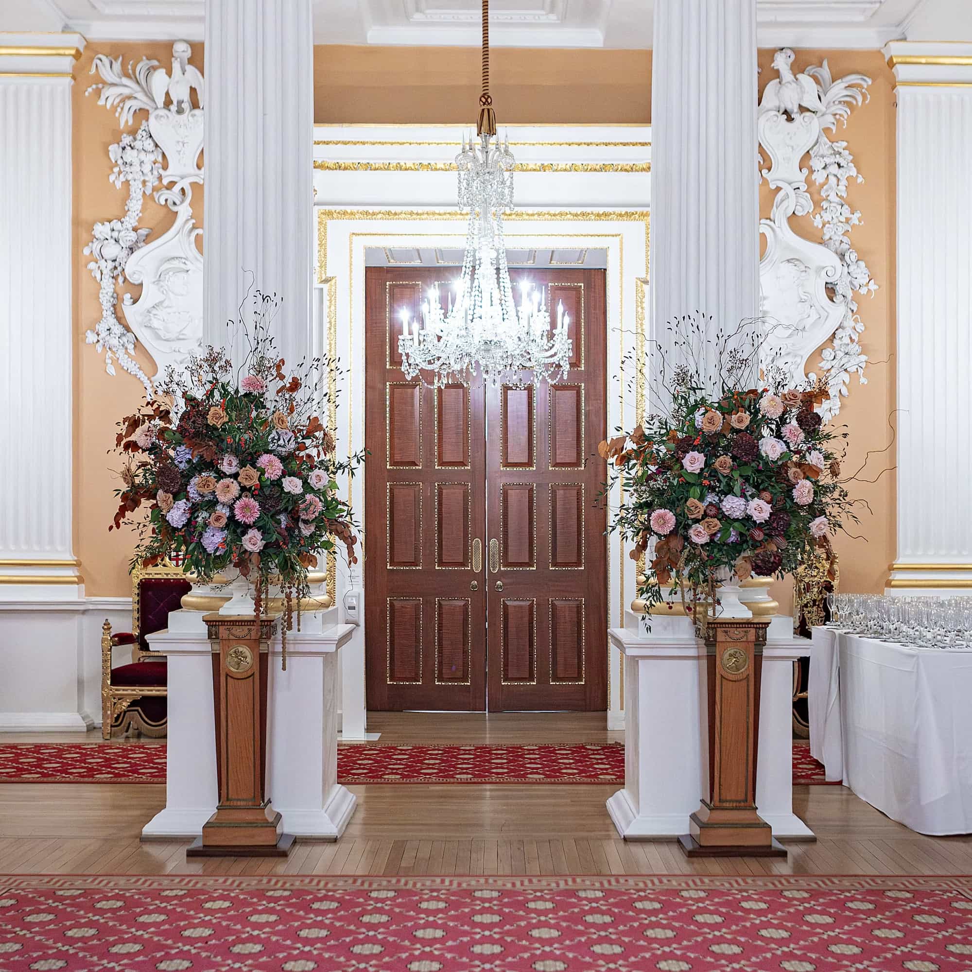 Unique custom floral displays on pillars to greet guests at the event entrance