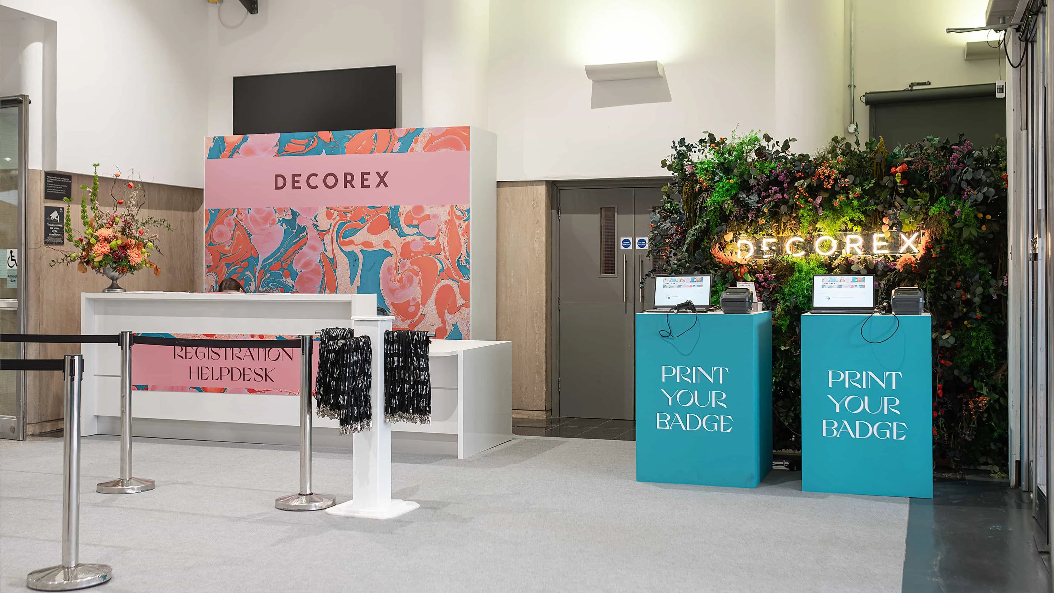 Decorex registration area enhanced by Amaranté London’s vibrant floral arrangements and a green wall backdrop, creating a welcoming and professional first impression.