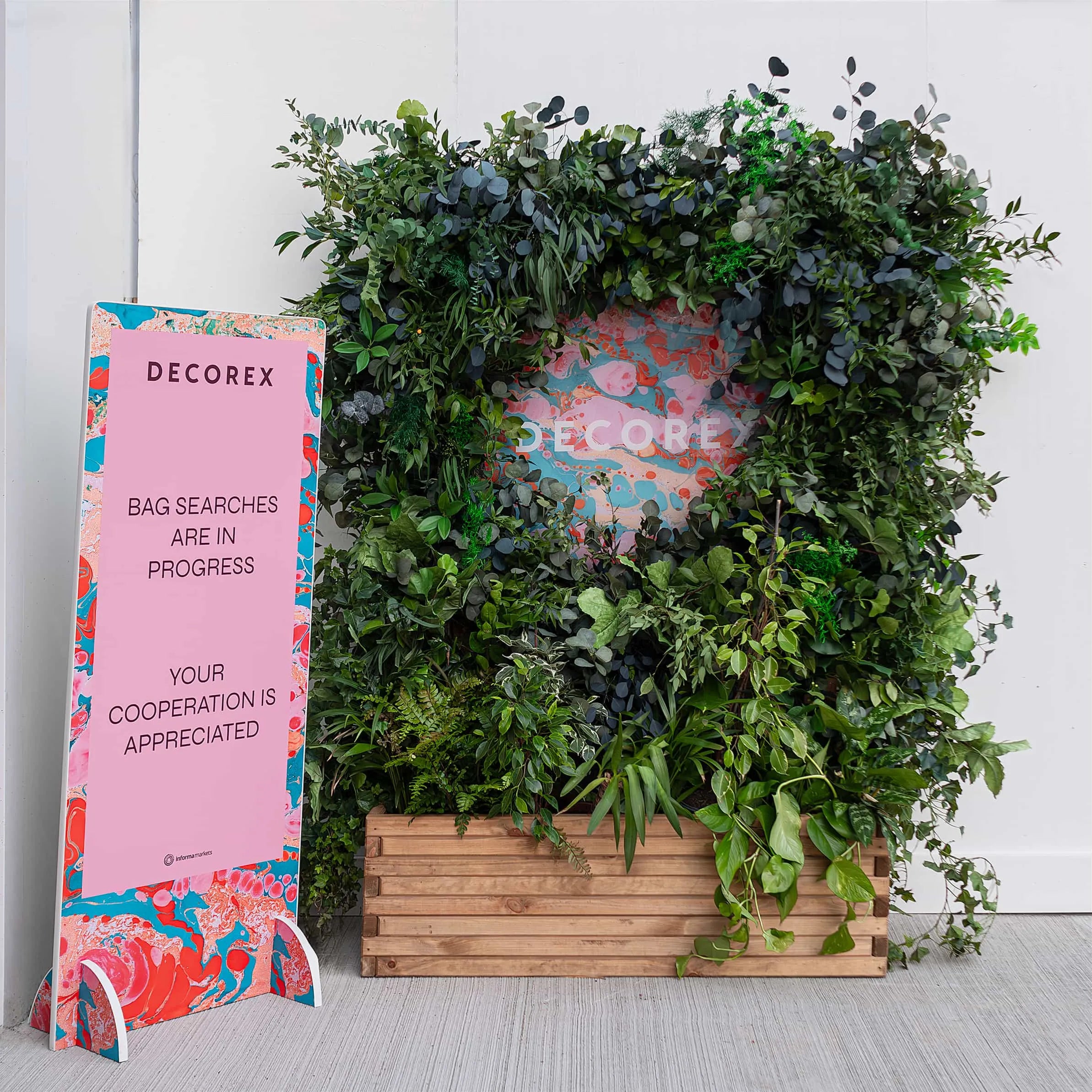 Bespoke floral wall at Decorex, featuring dense greenery and a subtle Decorex logo - event floristry by Amaranté London