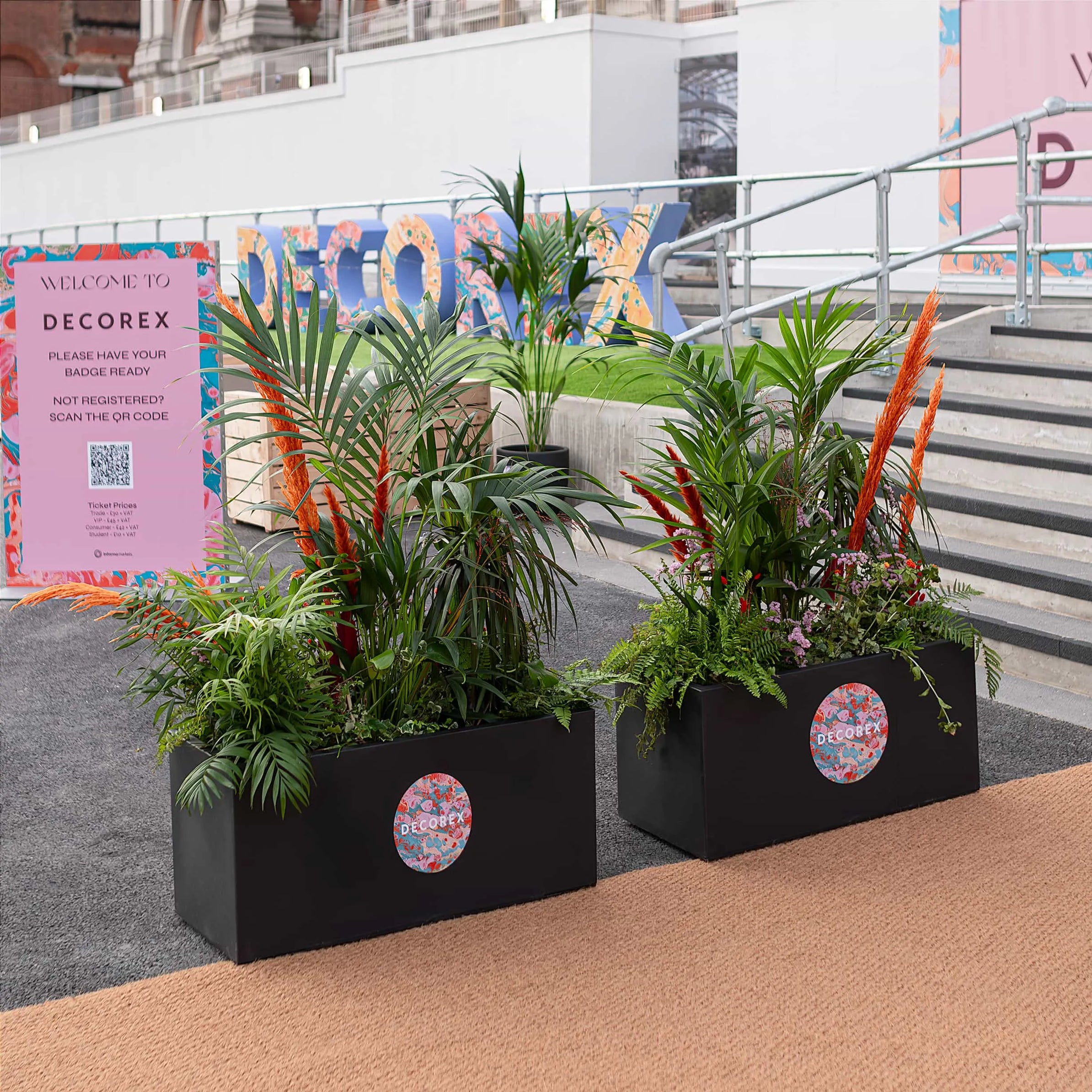 Vibrant planters at the Decorex entrance, artistically arranged with tropical plants and bright flowers, setting a tone of creativity and elegance - Plant Hire by Amarante London