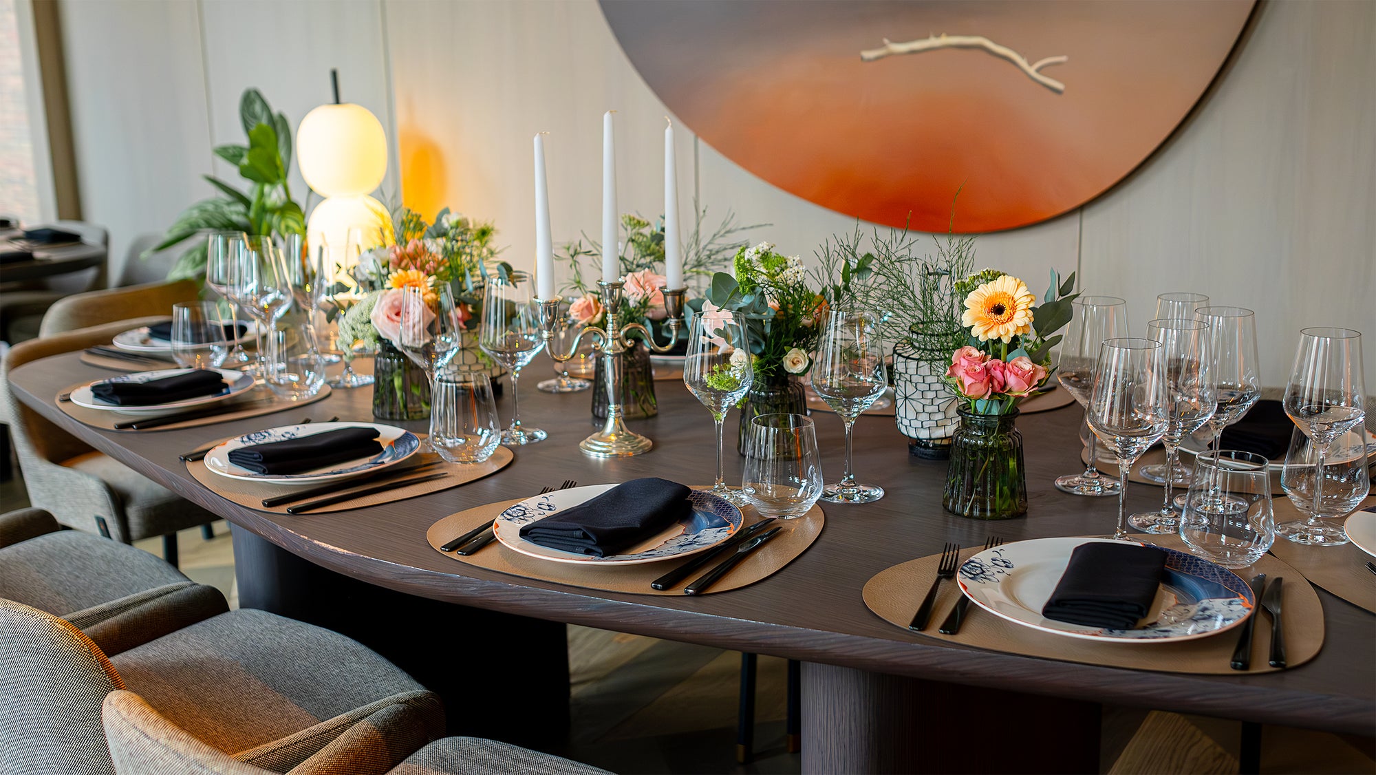 This is an image of the elegant corporate dinner setting with a round table at the Pan Pacific 5-star hotel, adorned with a bespoke floral centrepiece by event florist Amaranté London. This centrepiece features white hydrangeas, lush greenery, and delicate white blooms, creating a sophisticated atmosphere for this corporate event.