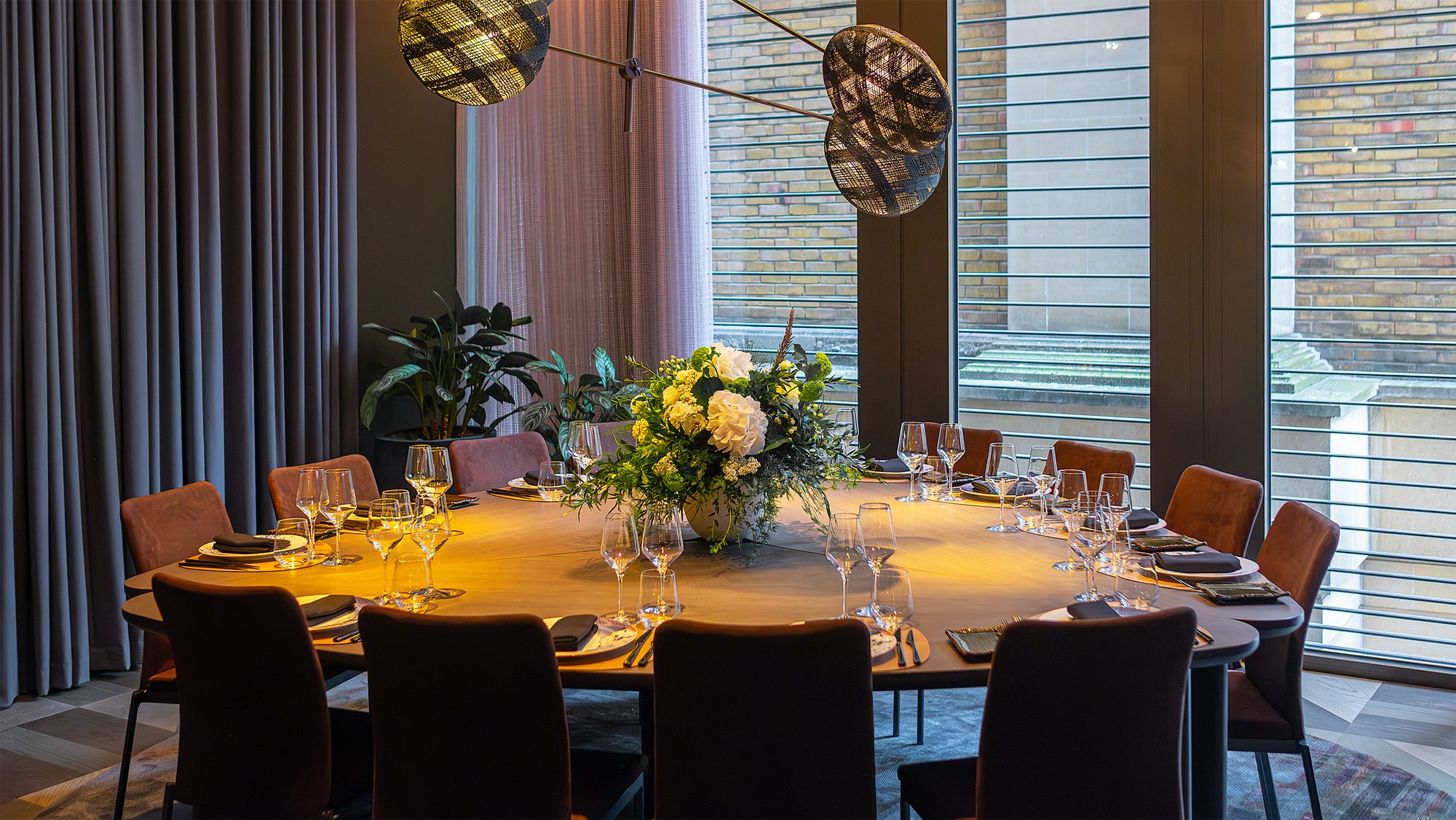 An elegant corporate dinner setting with a round table at Pan Pacific, adorned with a bespoke floral centrepiece by event florist Amaranté London, features white hydrangeas, lush greenery, and delicate white blooms, creating a sophisticated atmosphere, ideal for a corporate event.