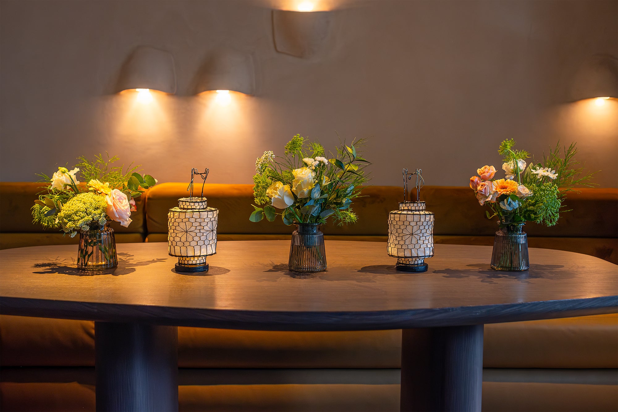 Close-up of elegant table settings at the Pan Pacific corporate event, with three small bespoke bouquets created and installed by event florist Amaranté London. The floral arrangements feature roses and greenery under warm lighting, creating an inviting and intimate atmosphere.