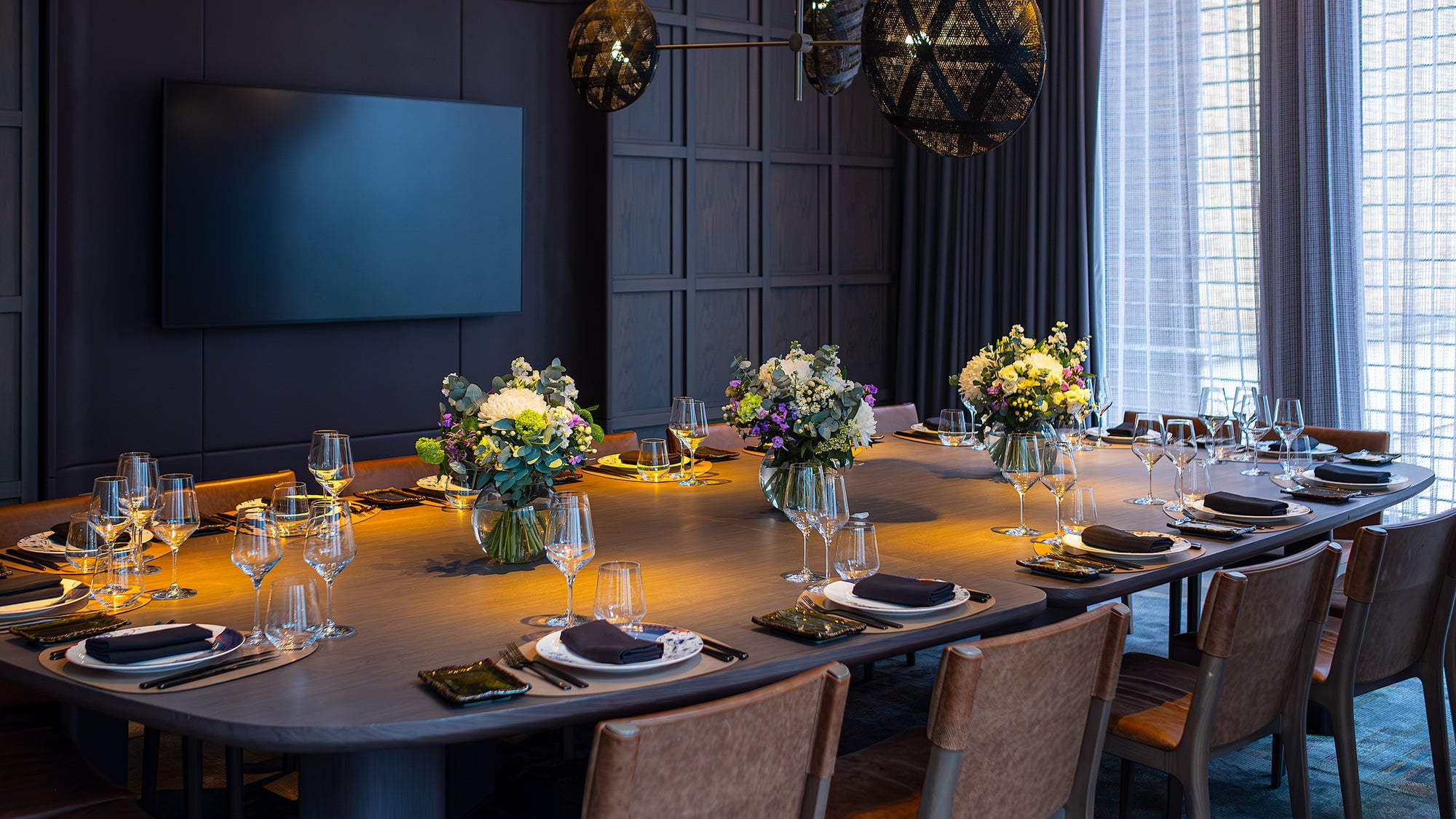 The luxurious corporate dinner arrangement at Pan Pacific features long tables decorated with bespoke floral designs by Amaranté London. The designs feature white hydrangeas, purple accents, and eucalyptus leaves, enhancing the elegance of this corporate event.