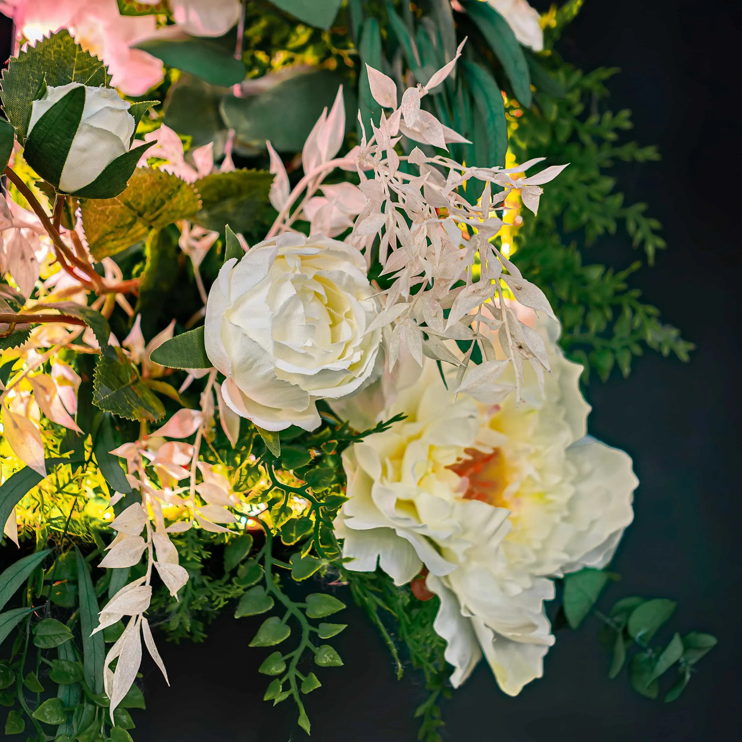 A close-up of an intricate floral display featuring large white roses and delicate pale foliage with a warm glow from ambient lighting, part of a decorative installation at STK Steakhouse.