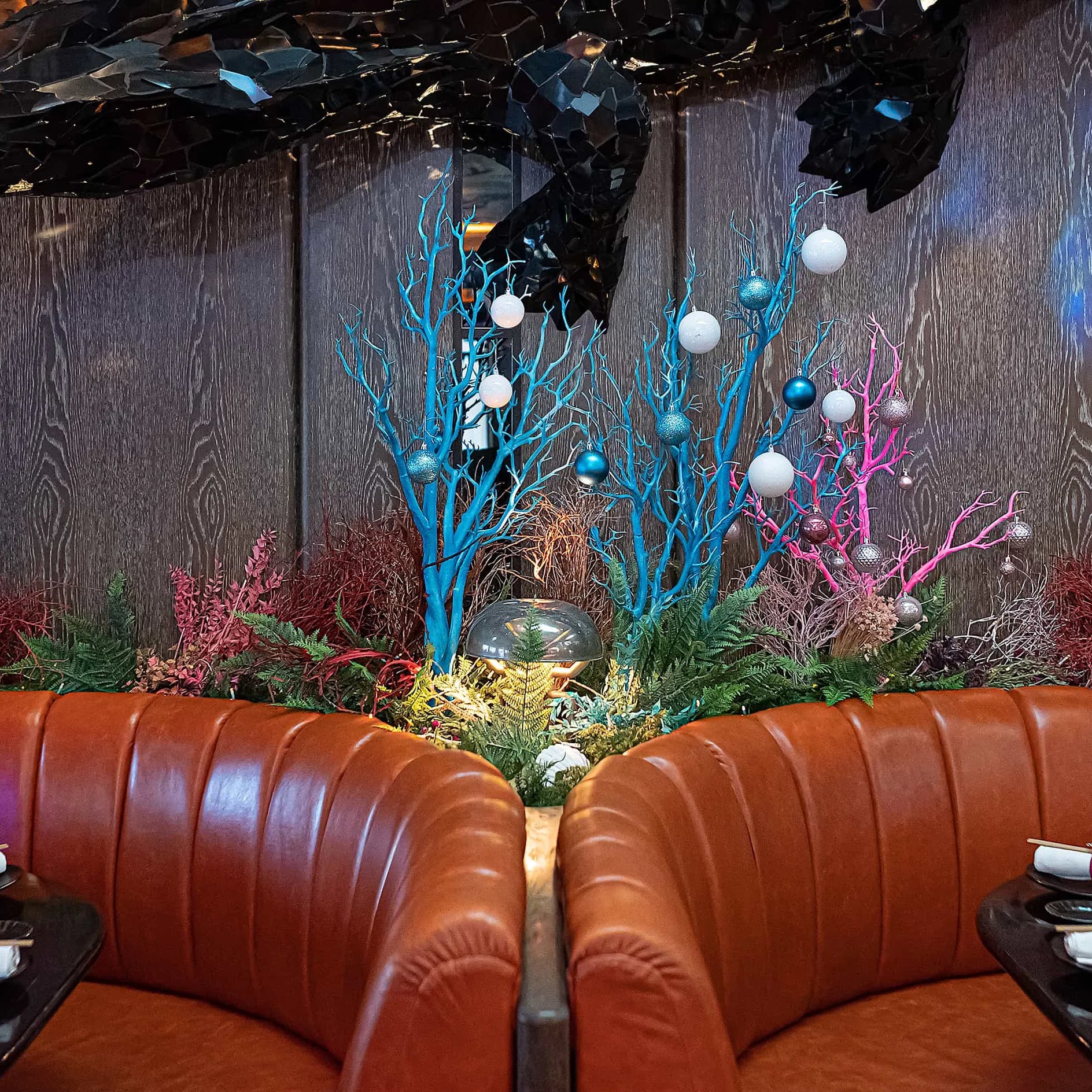 Elegant festive floral arrangement by Amaranté London inside Sexy Fish Restaurant, featuring a mix of dried flowers, coral-like stems, and silver baubles, creating a luxurious and ocean-inspired Christmas décor positioned in the lounge area near two luxury leather lounges.