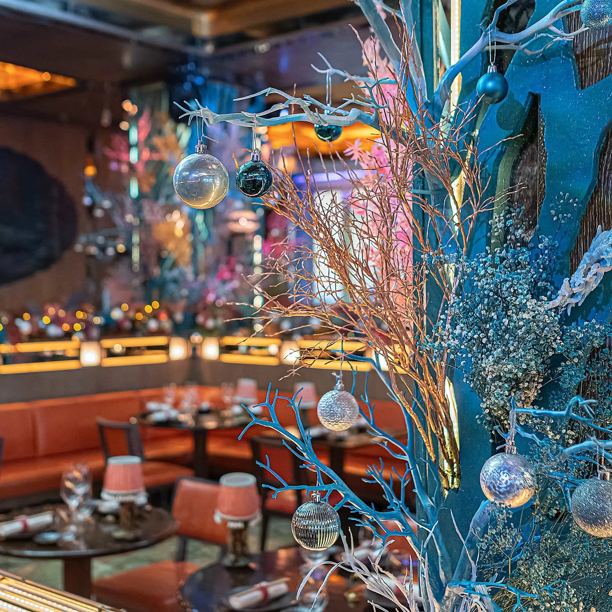 Luxurious Christmas floral décor by Amaranté London at Sexy Fish Restaurant showcases coral-like branches adorned with baubles, adding a festive and elegant touch to the sophisticated dining environment. Designed, created, and installed by Amaranté London, Event Florist.