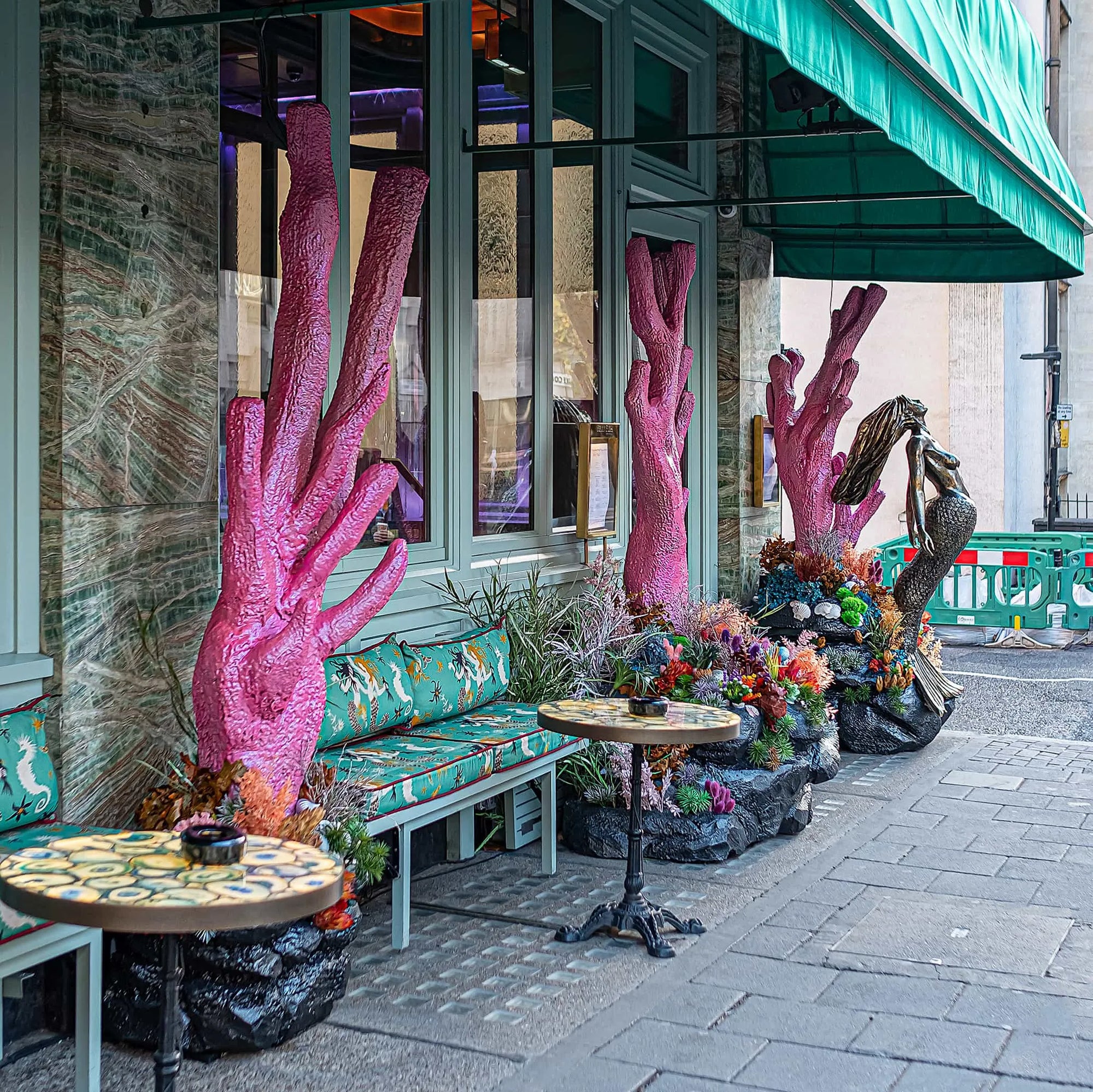 Outdoor Christmas floral arrangement by Amaranté London at Sexy Fish Restaurant, featuring vibrant pink coral sculptures and lush greenery, enhancing the restaurant entrance with a festive and oceanic theme. Designed and created by Event florist Amaranté London.