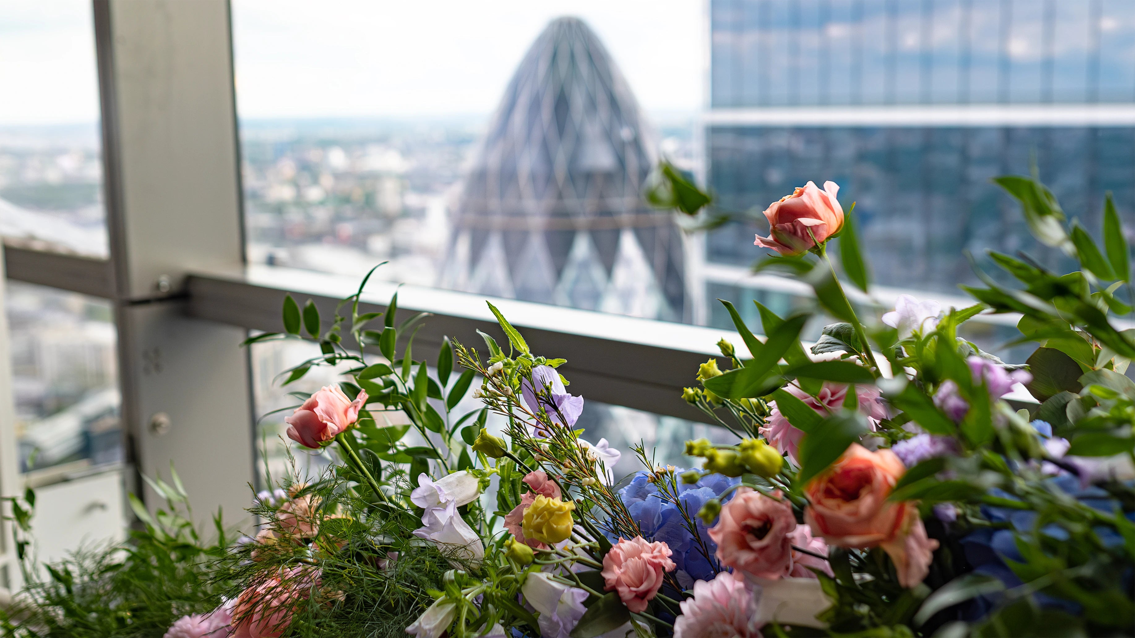 A close-up of a bespoke flower arrangement at Sushi Samba showcasing peach roses, purple lisianthus, and delicate greenery, creating a refined and festive look for the birthday event celebration Amaranté London.