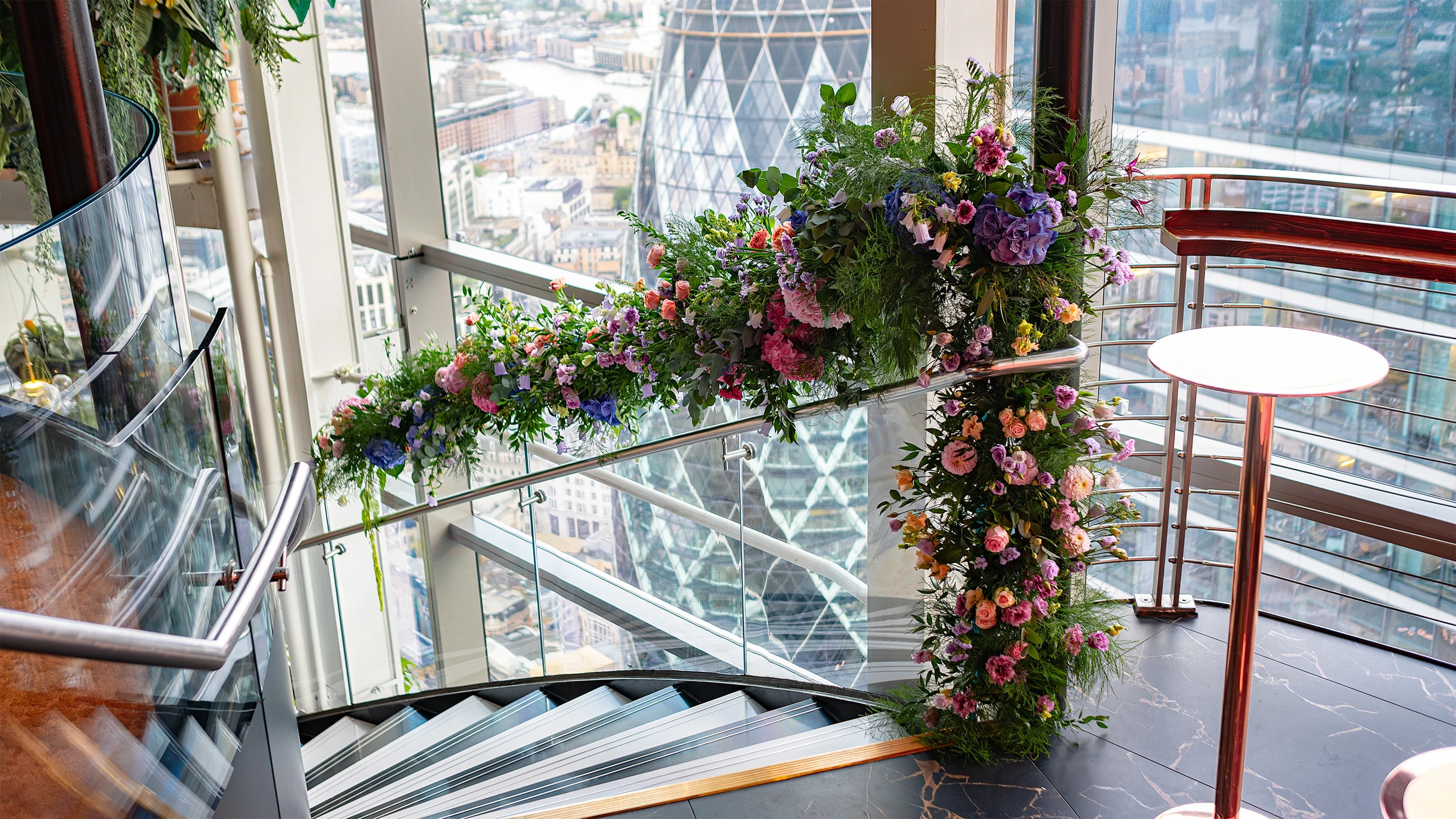 An exquisite floral wreath for a birthday event at Sushi Samba, adorned with pink roses, peach carnations, and lush greenery, perfectly complementing the venue’s sophisticated atmosphere with a blend of elegance and festivity - Floral design by event florist Amaranté London