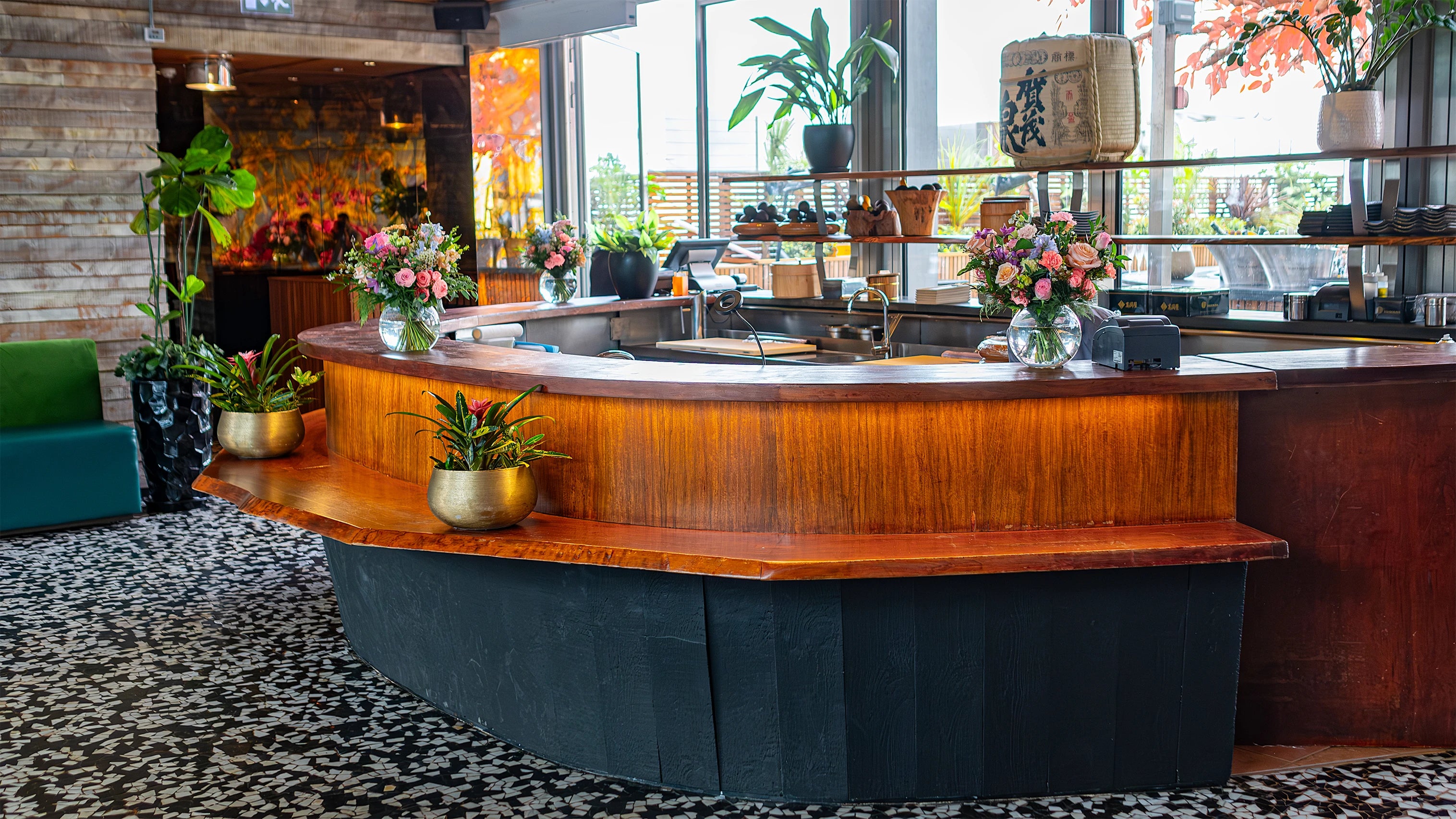 Multiple floral arrangements, each featuring blue hydrangeas and pink roses in golden vases, aligned on bar surface to create a cohesive and luxurious look for the birthday event celebration.