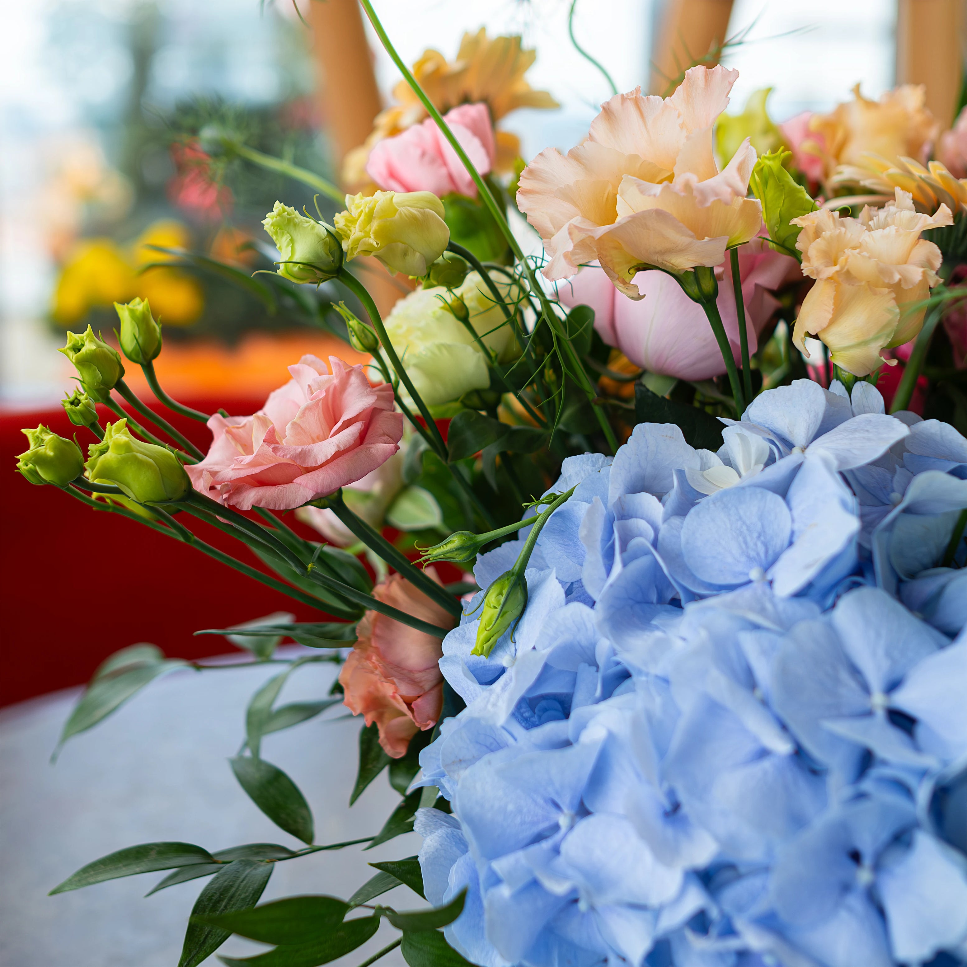 Table flower arrangements featuring blue hydrangeas, pink lisianthus, and lush foliage in golden vases enhance the elegance of the venue with a cohesive floral theme Amaranté London, Event Florist